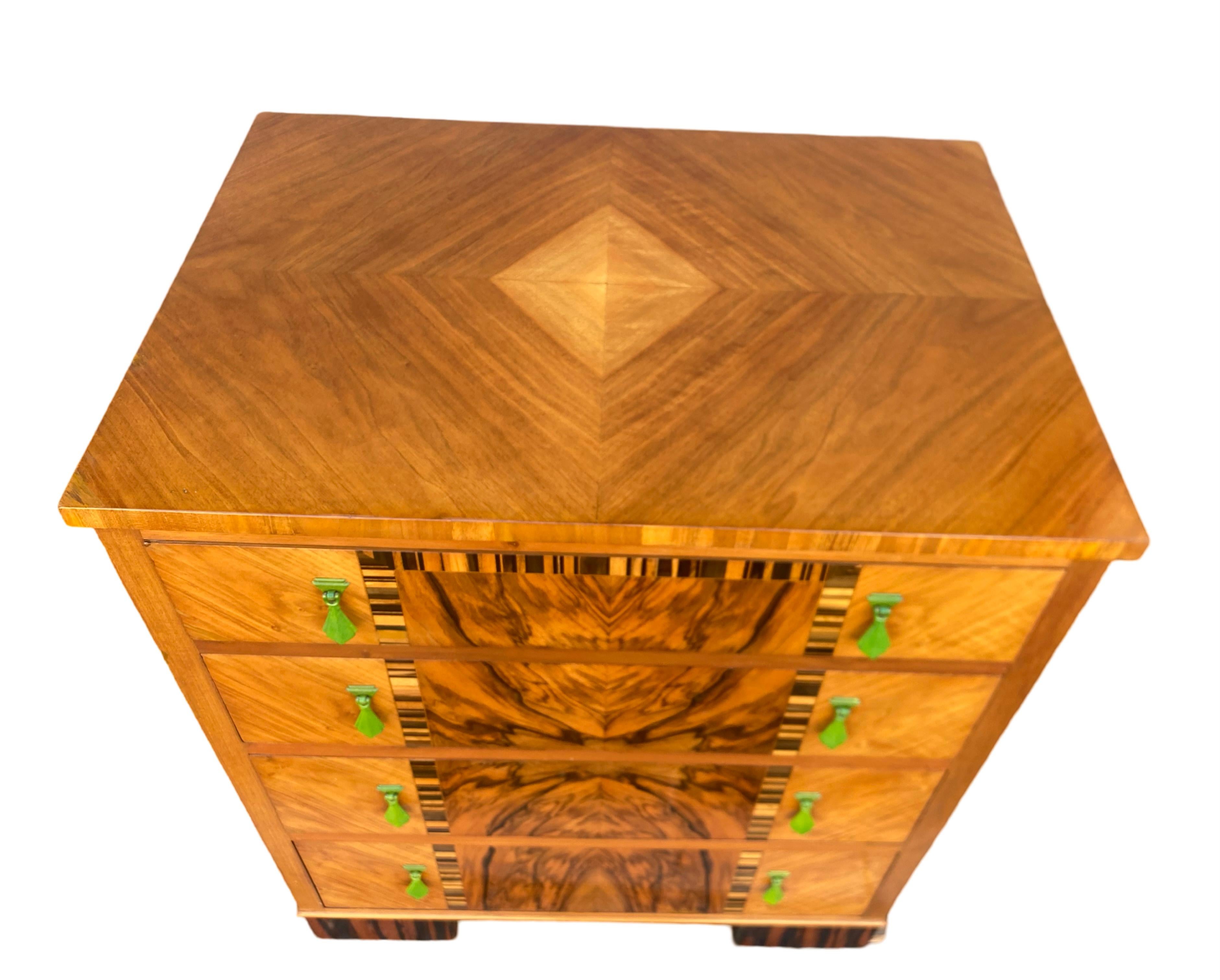 Une étonnante commode Art Déco. Les 4 tiroirs gradués fonctionnent sans problème et ont leurs belles poignées d'origine en vert émeraude. Les façades des tiroirs sont décorées de placages de caramandal et les pieds de beaux maccarts. La commode est