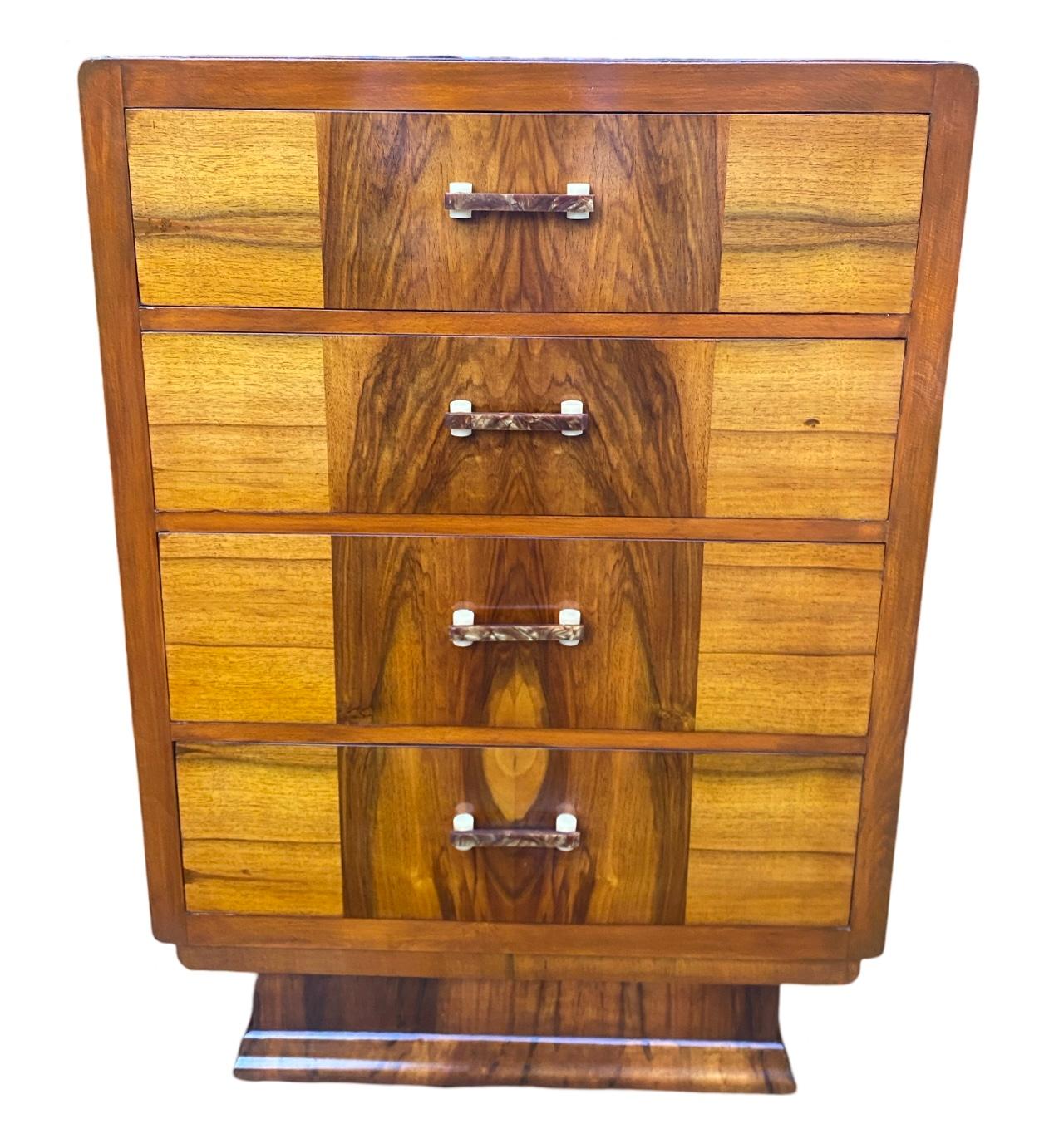 Siamo lieti di offrire questa favolosa cassettiera in noce Art Decor degli anni '30 con 4 cassetti graduati, ognuno dei quali è decorativamente impiallacciato per abbinarsi alla parte superiore della cassettiera e ornato con le maniglie originali in