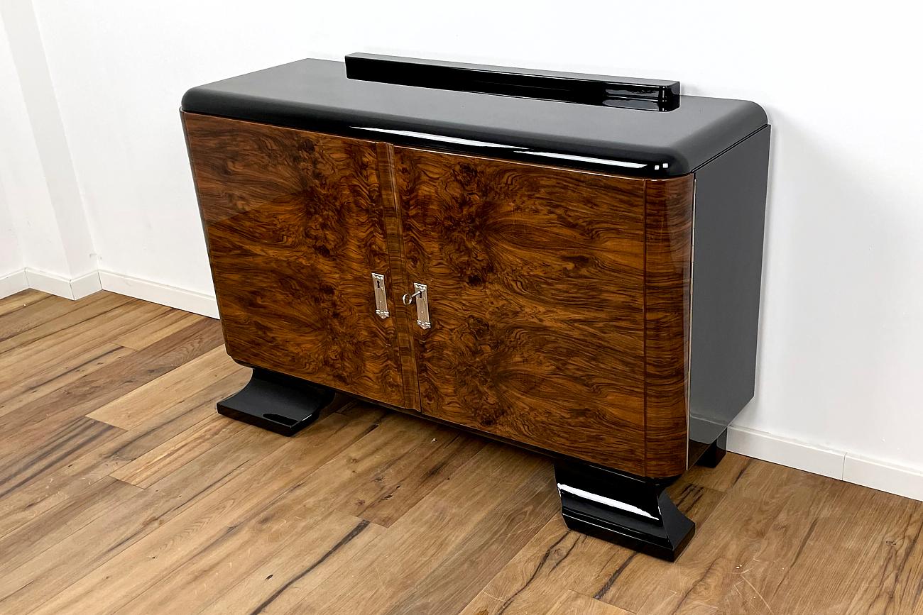 Nice little chest of drawers from the German Art Deco. The combination of the black piano lacquer and the Kaukassischer walnut make this furniture an absolute eye-catcher. The entire piece of furniture is provided with a multi-layer structure of