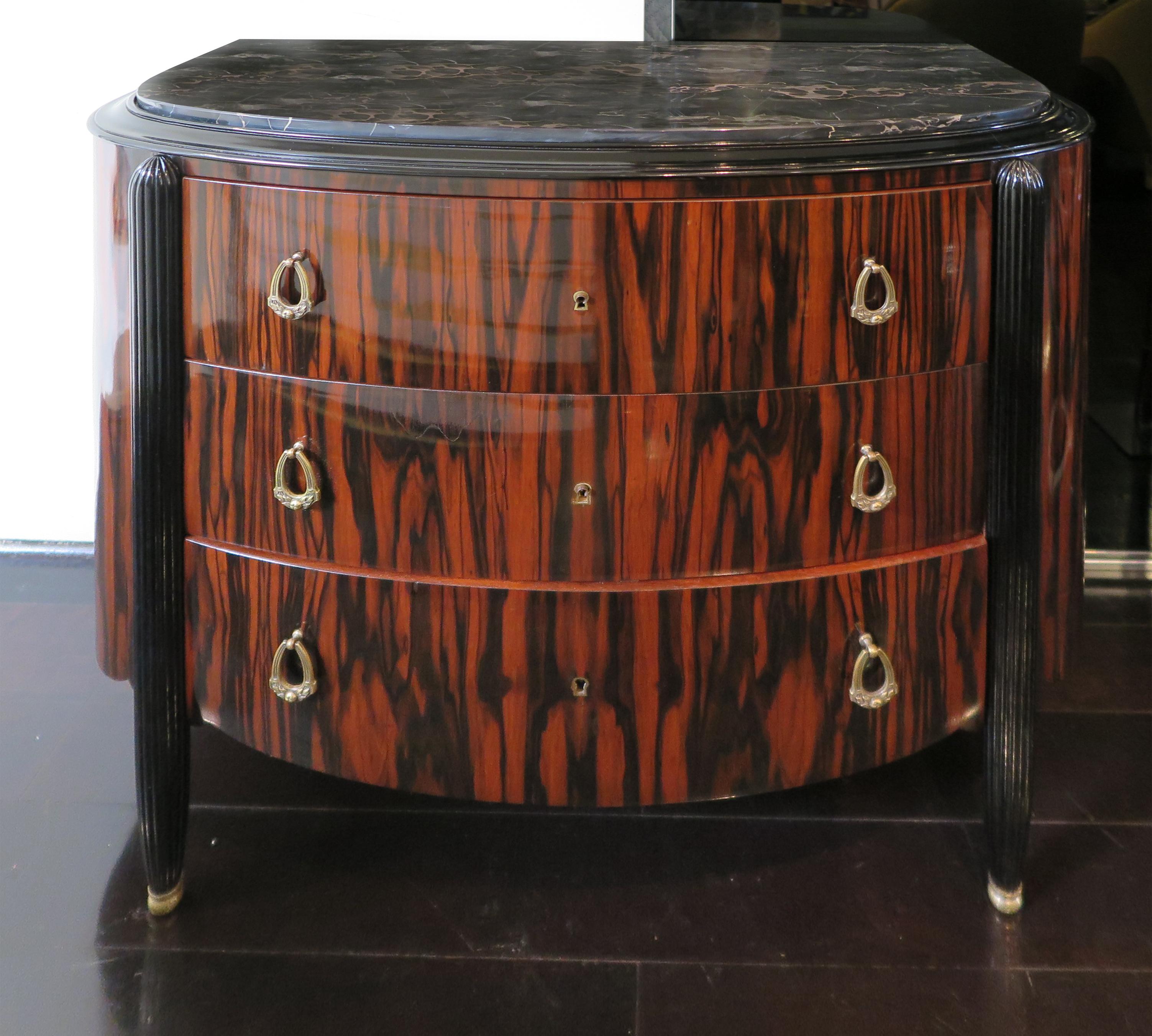This stunning French Art Deco chest of drawers features a Macassar Ebony body and black lacquer ribbed legs. The top showcases original black marble with white veining and the bottom features a delicate scalloped detail. Attributed to Michel Dufet,