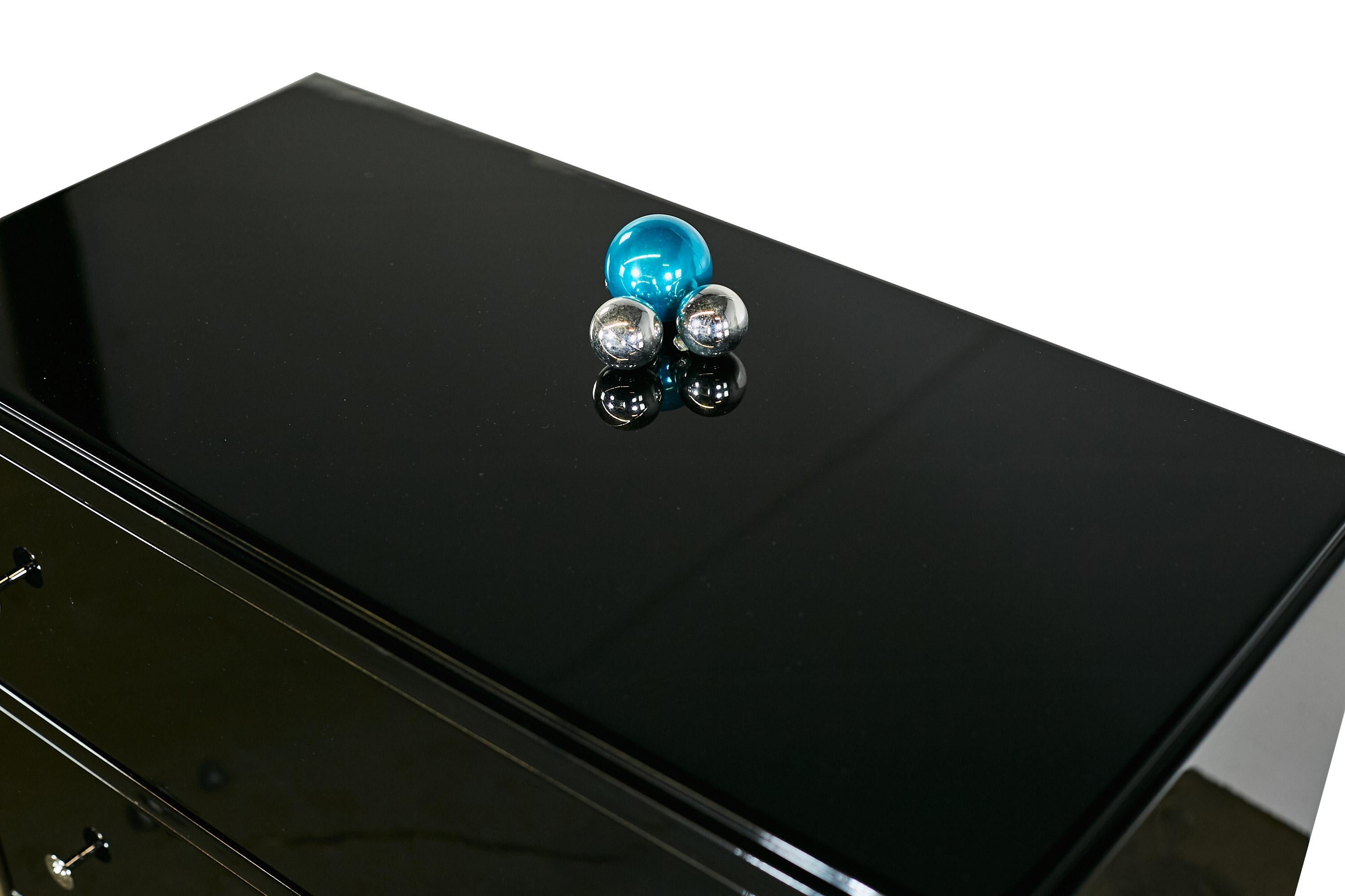 Schöne kleine Kommode mit sehr elegantem Klavierlack und Chromgriffen. Die Kommode hat drei Schubladen und ist mit runden Chromgriffen ausgestattet. Die Oberfläche ist mit einem Hochglanzlack versiegelt worden. Die schwarze Oberfläche wurde lackiert