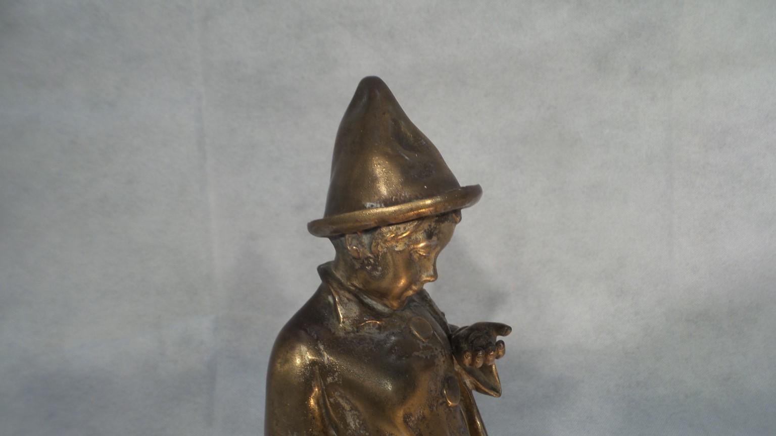 A wonderful and charming Art Deco lamp on marble. The sculpture is spelter lined with a fine layer of bronze . It features a small boy dressed as a clown. In one hand he has a violin and in the other he clutches a handful of coins. Presumably his