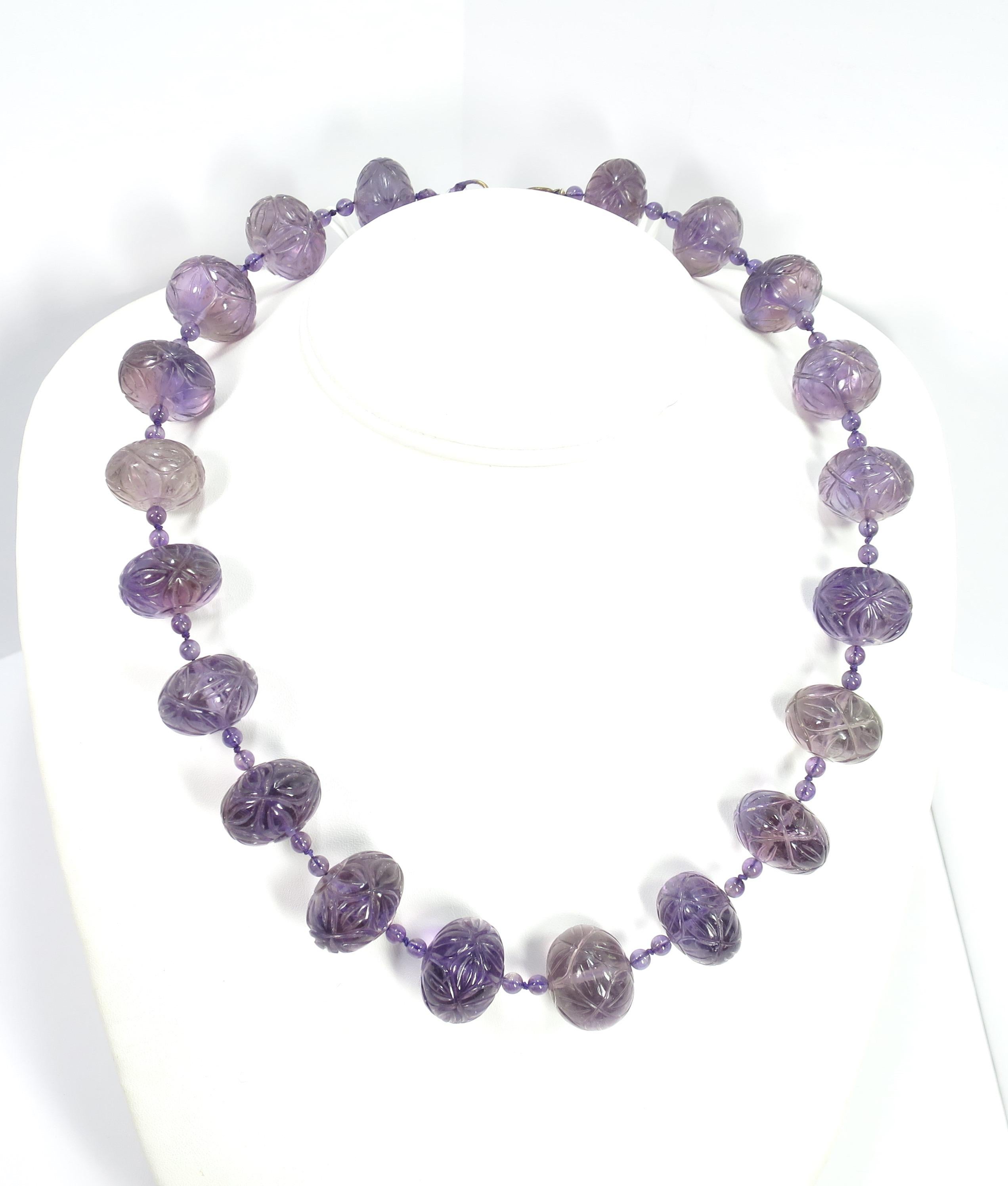 Offered here is an Art Deco Chinese carved amethyst bead necklace from the 1920s. Each hand-carved bead is decorated in a geometric floral pattern; the color varies slightly from bead to bead, as befits the natural state of the amethyst stones. In