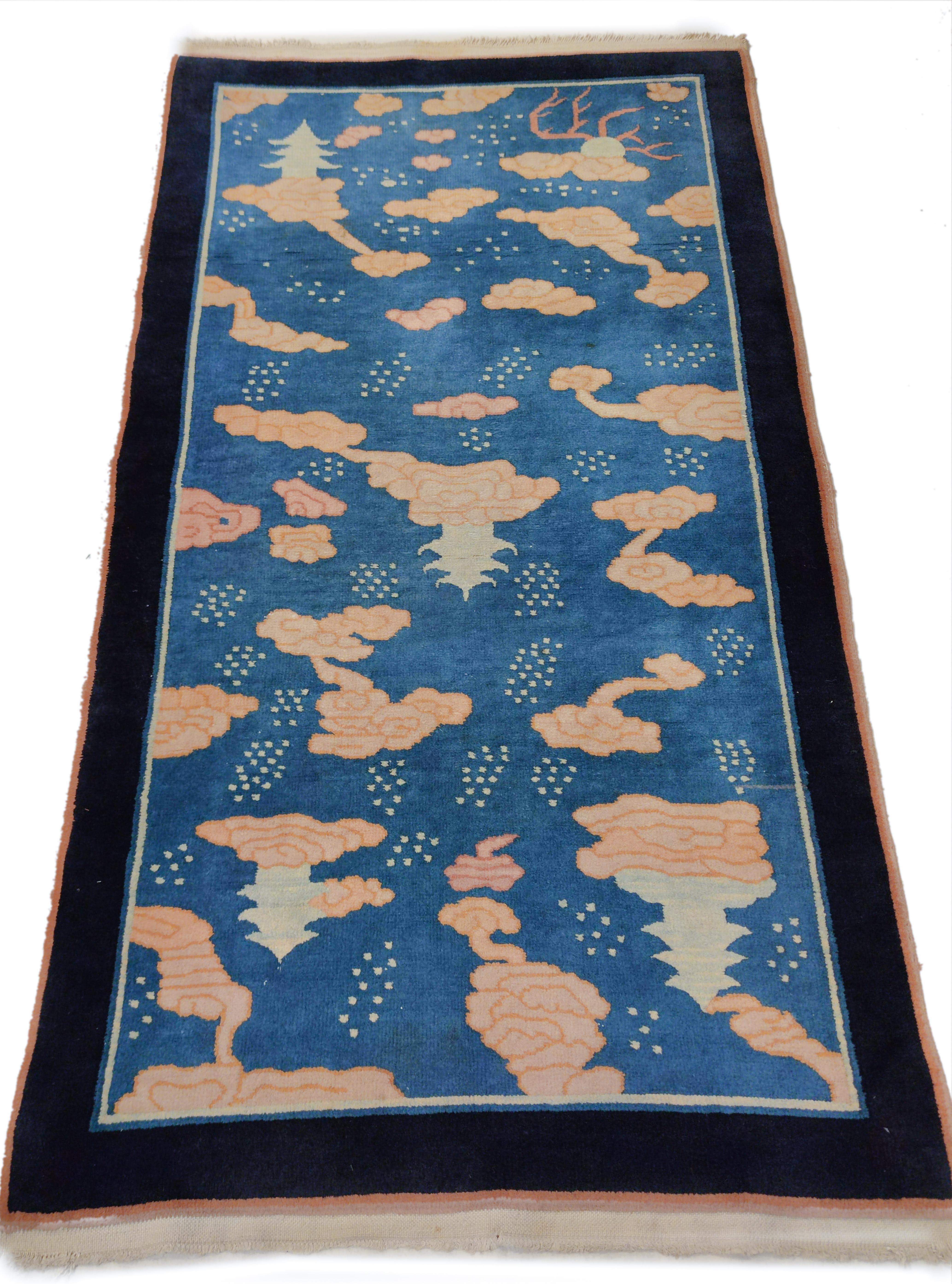 Un tapis à fond bleu avec un motif ascendant de nuages stylisés tissé par Nichols & Co, une importante société américaine basée à Tianjin, connue pour ses tapis très robustes et résistants, généralement tissés avec des motifs floraux typiques de la