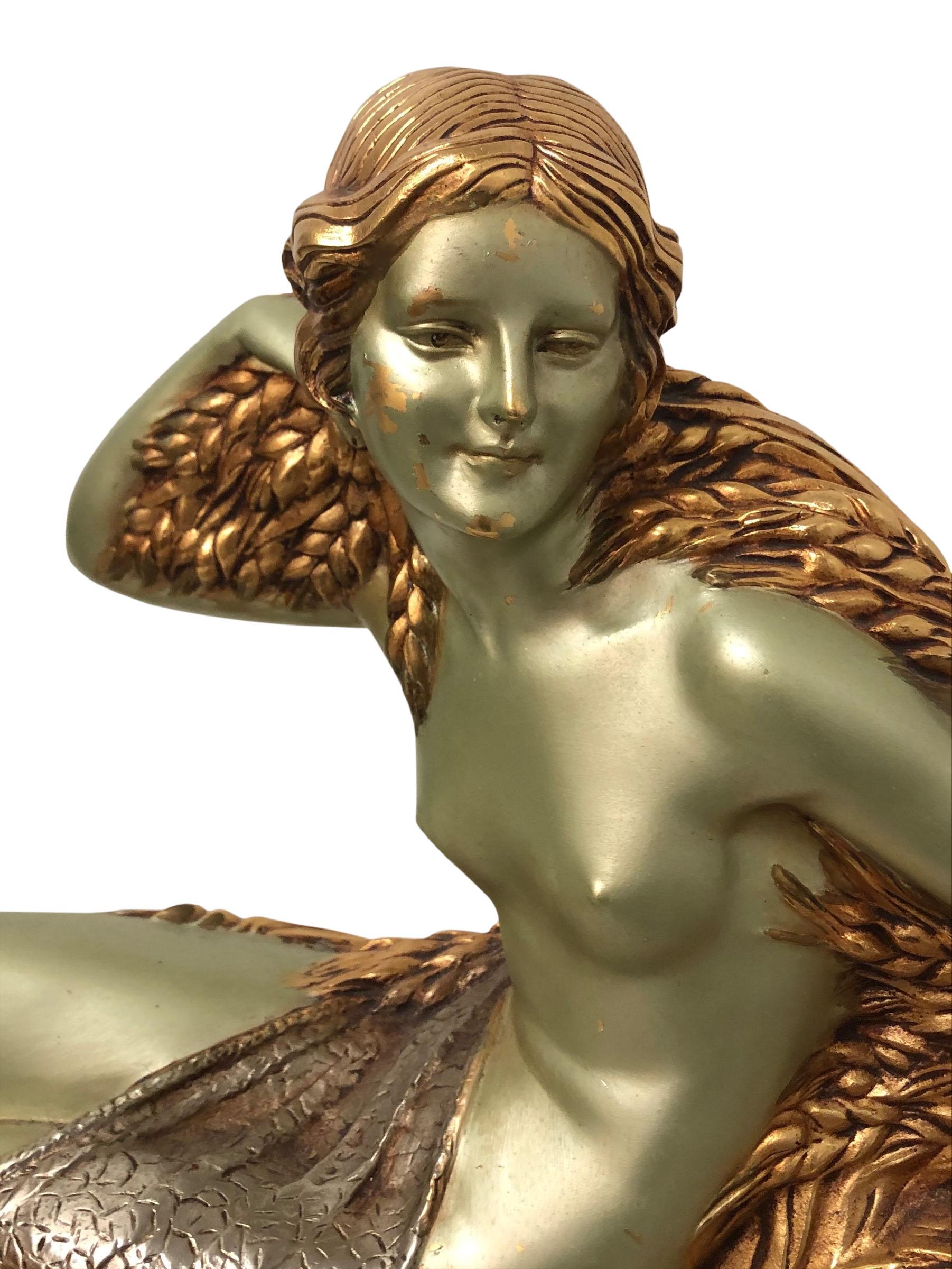 1920s solid bronze sculpture of a seated flapper girl. She is solid bronze with a gold and silver and green patina on a marble base. Signed by the artist, Demetre Chiparus. The marble is Beige with a pink cast to it.

Romanian artist Demetre
