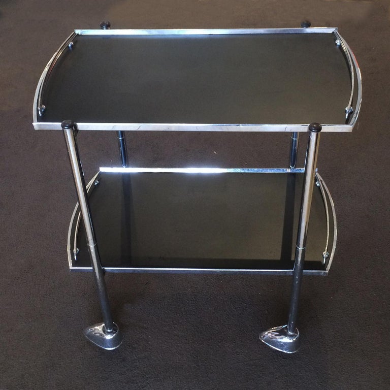 Art Deco chrome drinks cart, with black melamine shelves with chrome edge all around trays, and guard rails at all ends, including the original chromed metal hubcaps, all intact and working as they should. The rubber tyres and rims are also good,