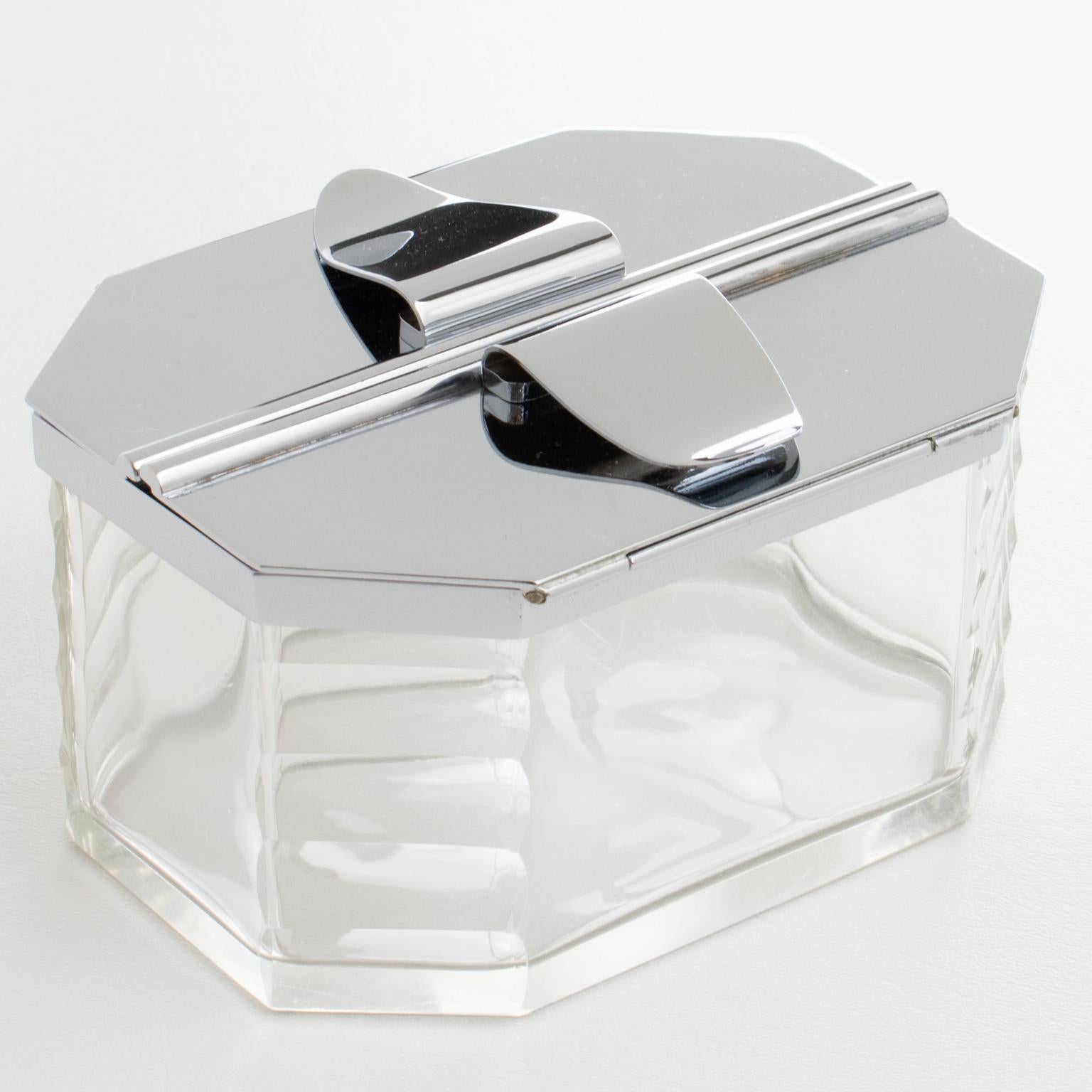 L'orfèvre français François Frionnet, Paris, a conçu et fabriqué cette élégante boîte à biscuits décorative Art déco en chrome et en cristal dans les années 1930. Le design moderniste et minimaliste se caractérise par un récipient géométrique en
