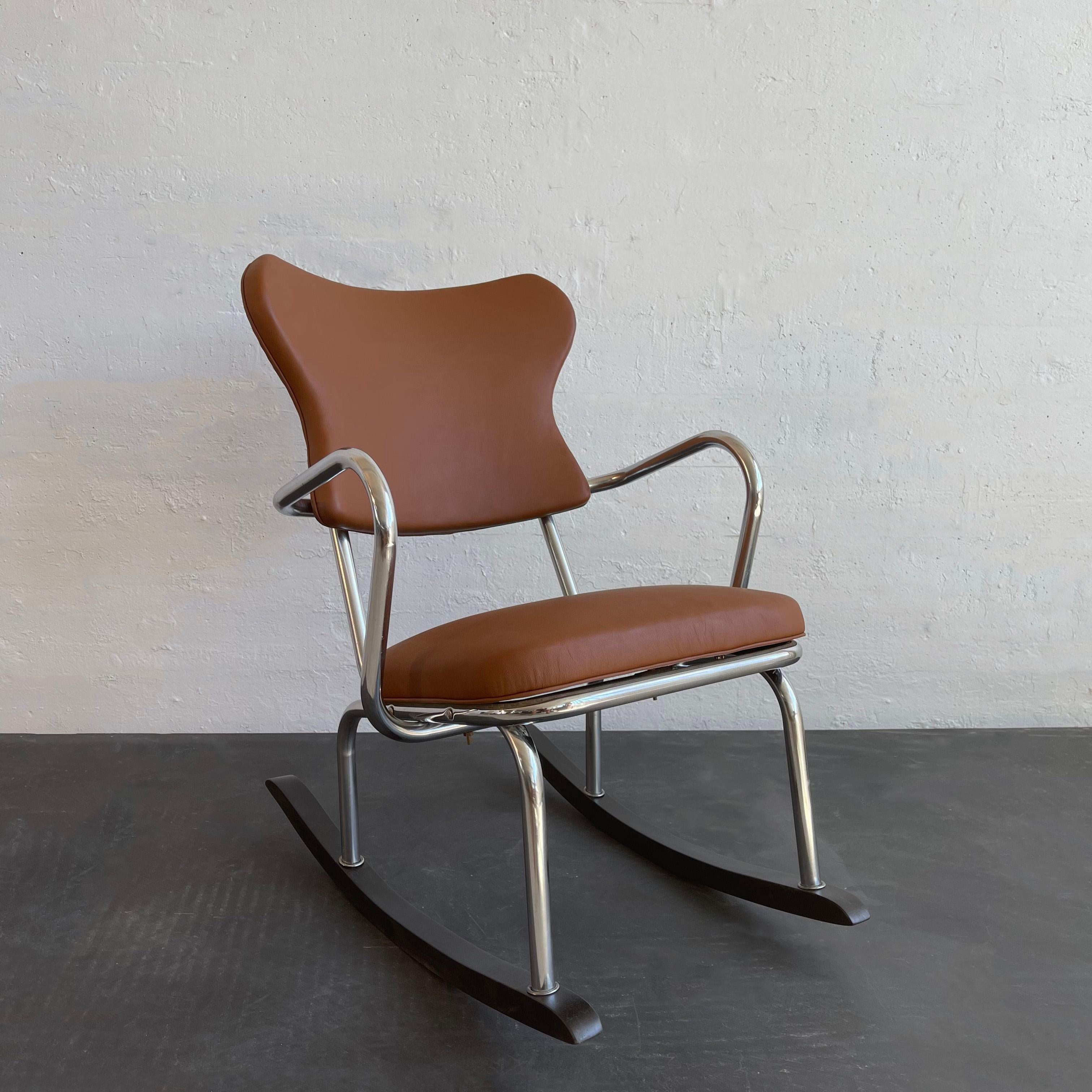 Art deco, machine-age rocking chair in the manner of designers Gilbert Rohde and Kem Weber features a bent chrome frame on black lacquered wood rockers with contoured back. The back and seat are newly upholstered in burnt sienna leather. 