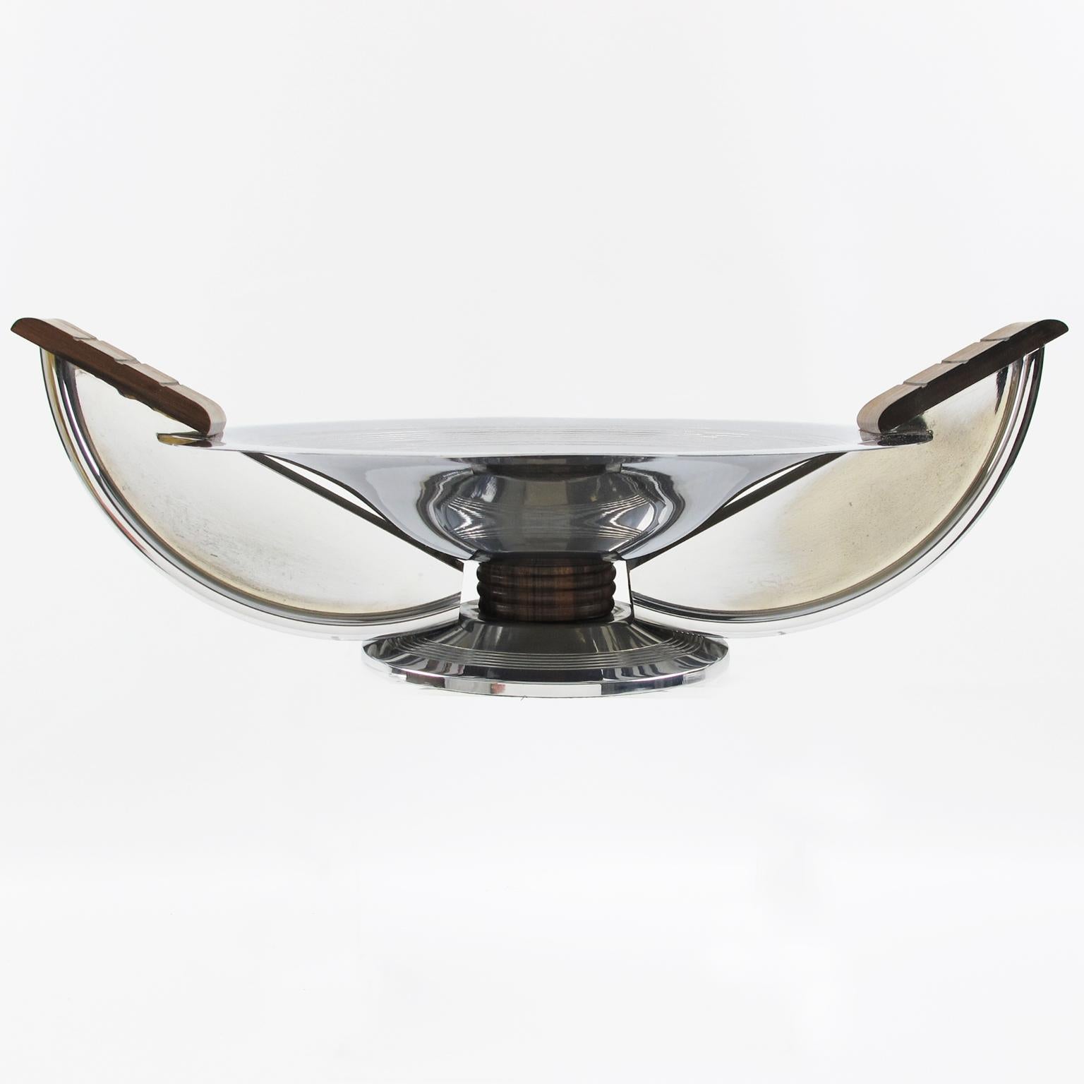 This stylish Art Deco centerpiece or decorative bowl was hand-crafted by French silversmith Massabova, Paris, in the 1930s. The round geometric shape has wing handles. The chrome-plated metal body is ornate with carved Macassar wood and complemented
