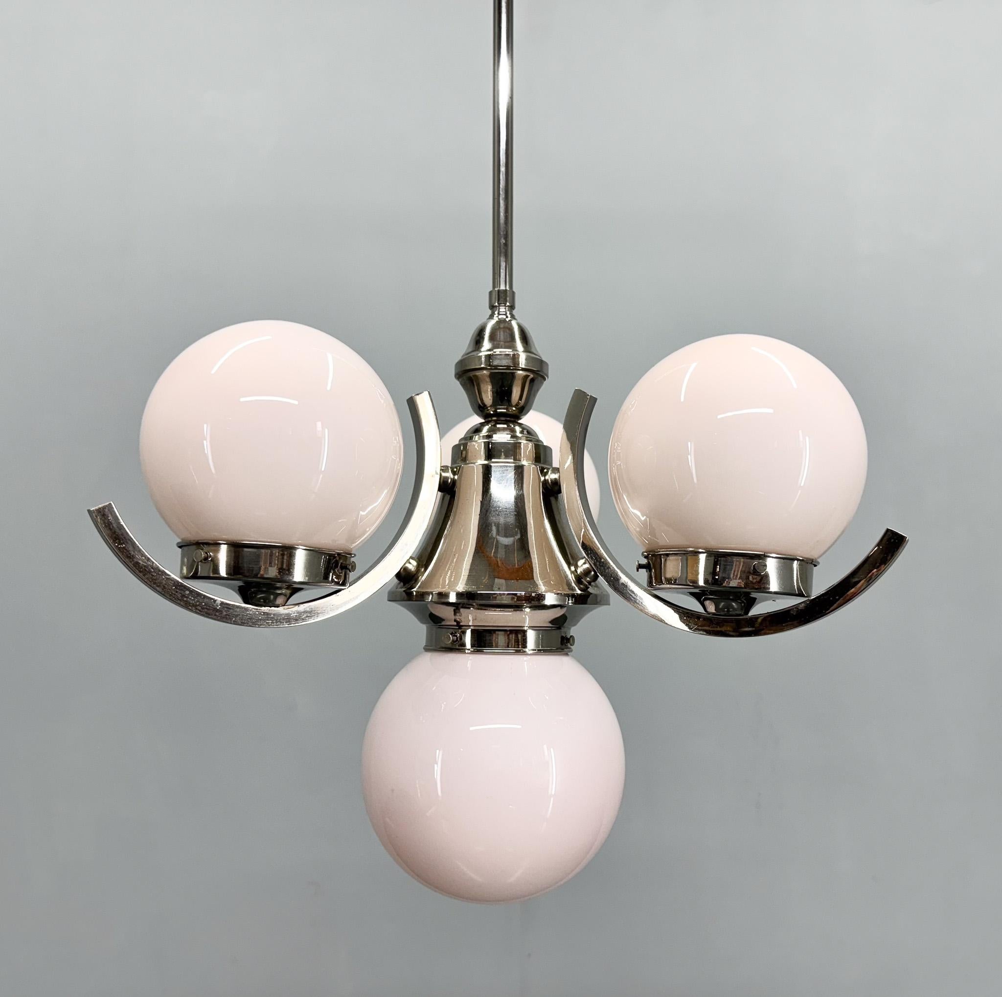 Art deco chandelier made of chrome with four glass balls, rarely seen in this pinkish colour. Made in former Czechoslovakia in the 1930s. 
Original, fully functional wiring. Bulbs: 4 x E26 (E27). US wiring compatible.
