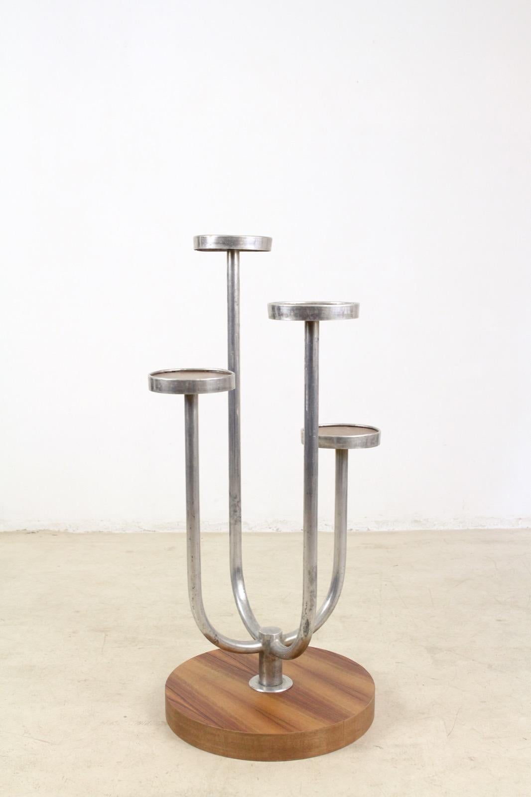 Tubular steel plant stand with walnut veneered plates and base. It was produced in the 1930s. There are some minor fading on the base.