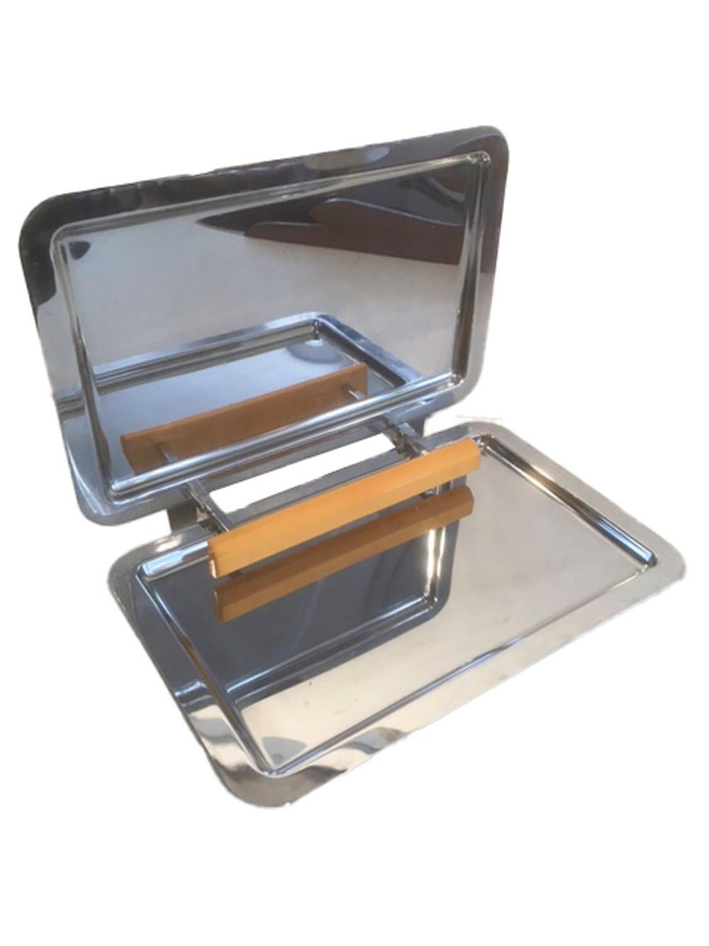 Manning-Bowman chrome folding tray with yellow Bakelite handle, the two rectangular halves with a flat rim around a central surface with a central Bakelite handle connected at the hinge. The tray folds like a clamshell enclosing the handle for