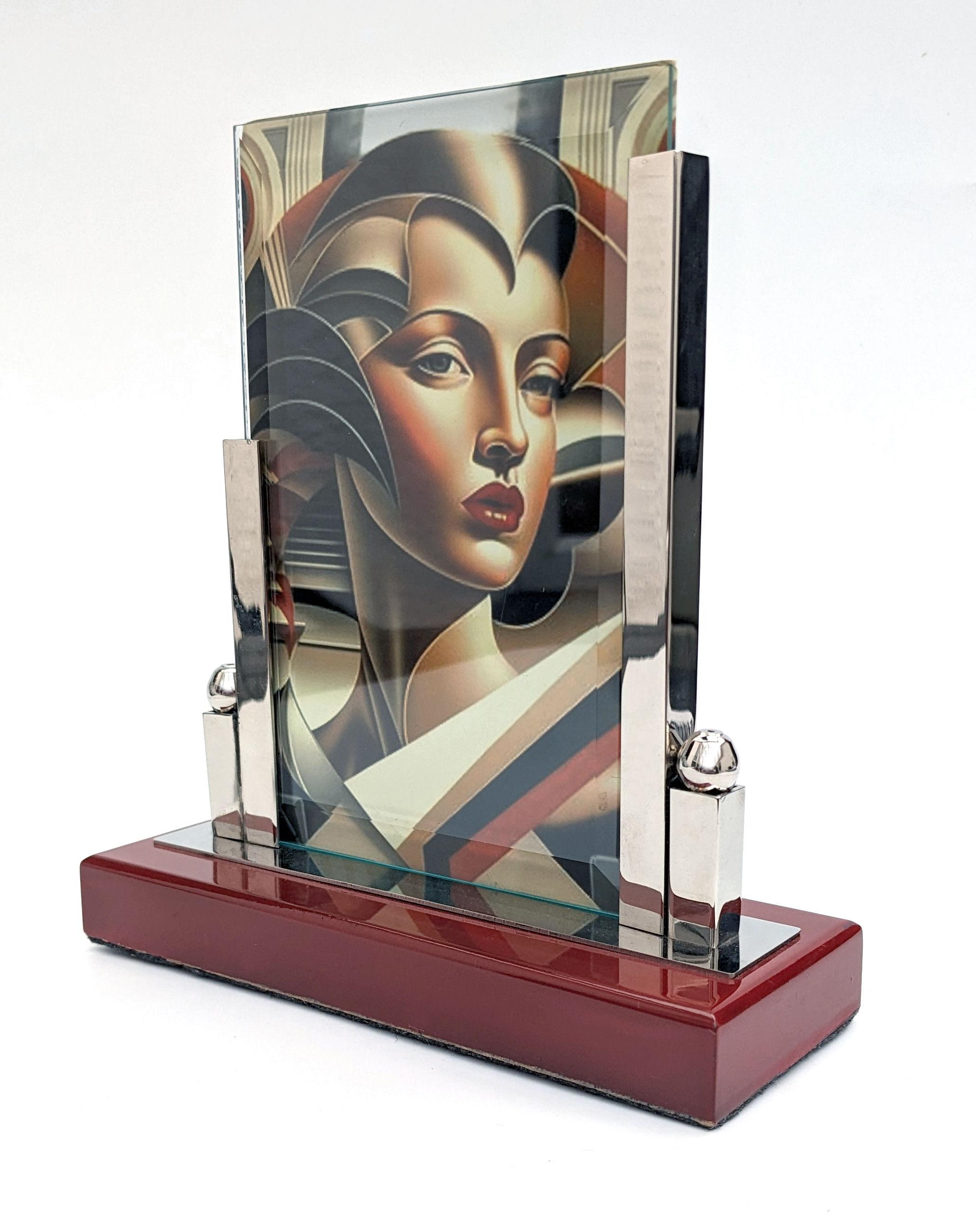 Superb 1930's Art Deco modernist free standing picture frame in chrome and glass. The frame has two pieces of glass which slot into the chrome stand. You can display a picture both to the front and back. Highly lacquered red wooden base with