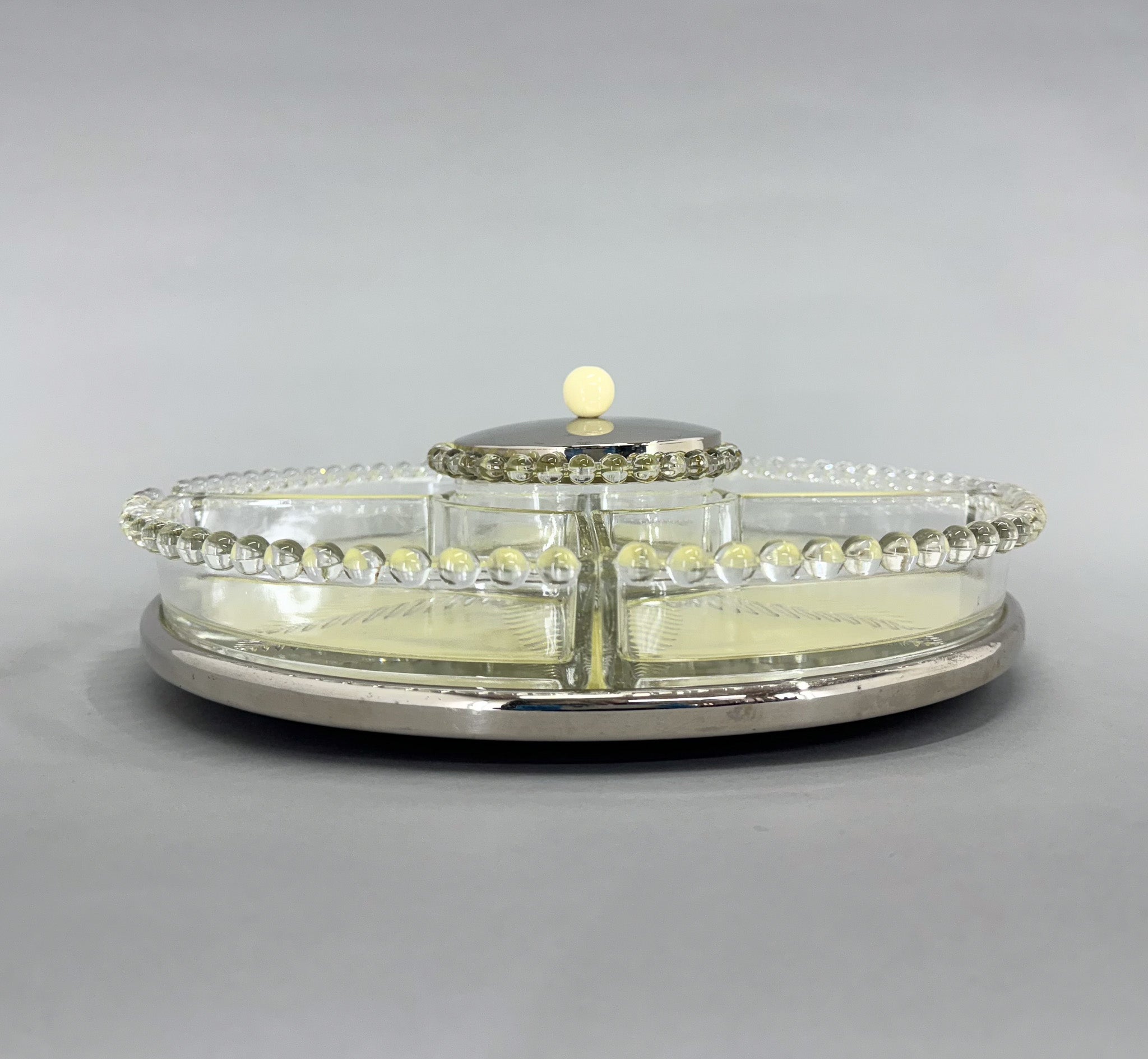 Art deco rotating 'Lazy Susan' tray. There are 4 glass containers and one round bowl with a chromed lid in the middle. If you remove all the glass, you can use it as a cake platter. Very good vitńtage condition.
