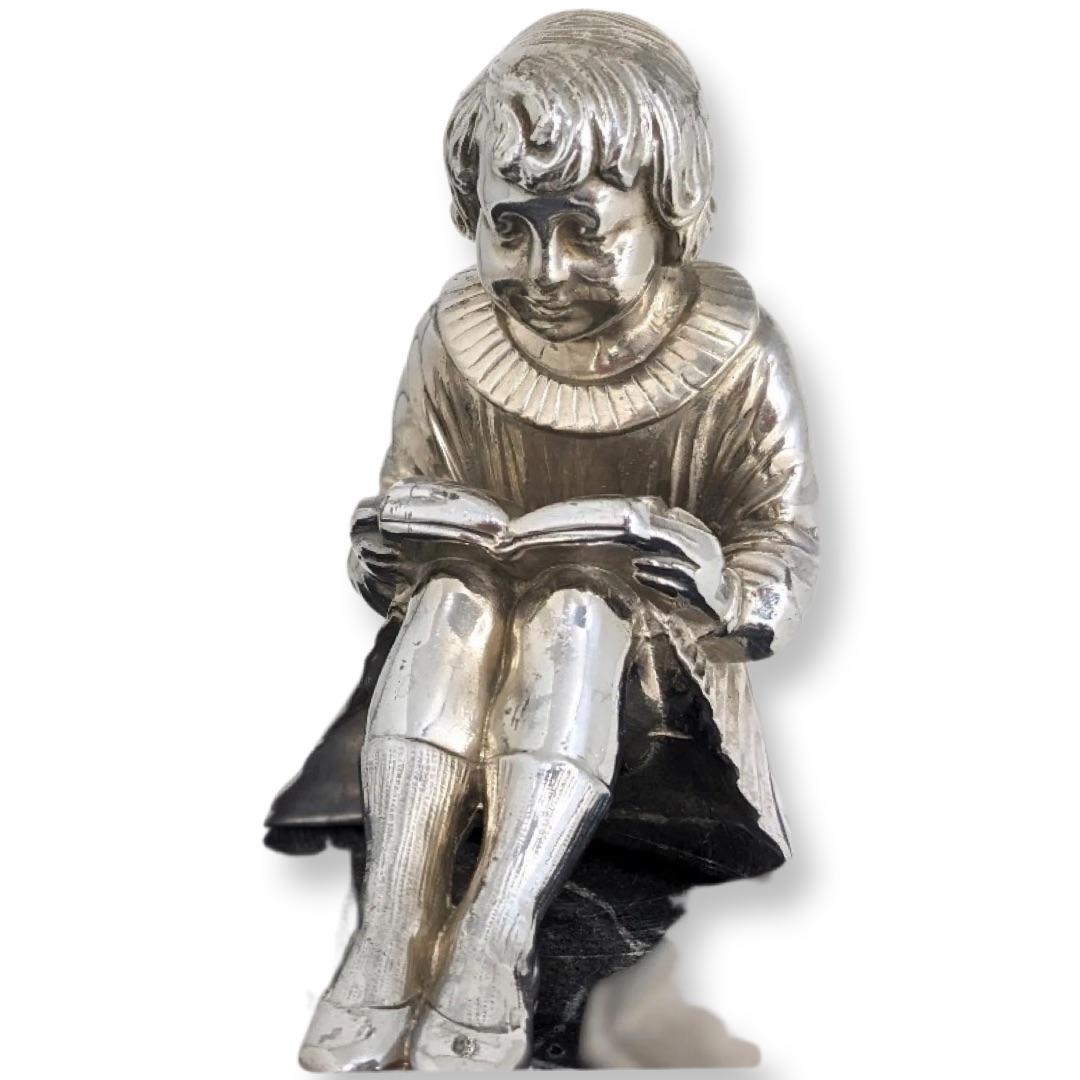 Circa 1930s a charming chrome on marble depiction of a little girl seated reading a book next to an inkwell. She sits upon a variegated black marble plinth with chased recess for a fountain pen. The inkwell retains its original glass inset. The size