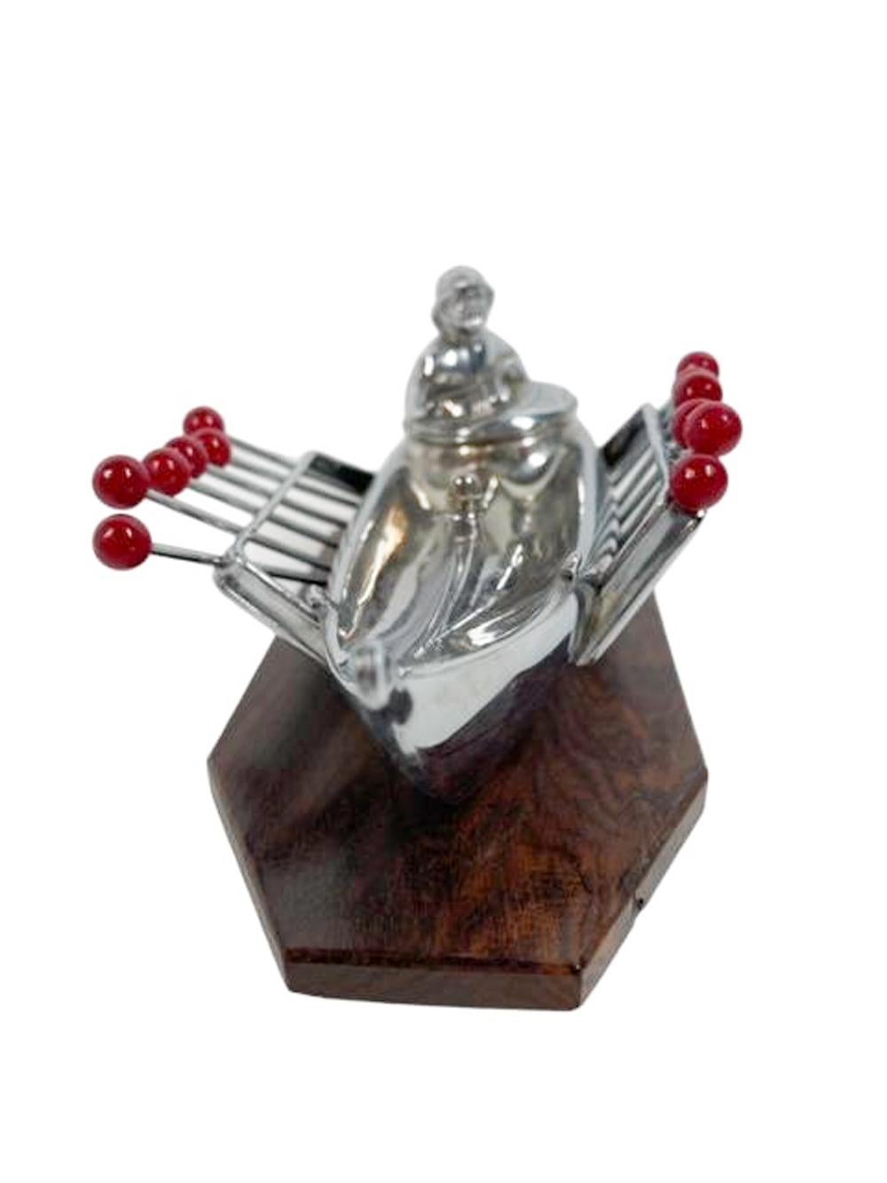 Art Deco chromed figure of a fisherman in a dory wearing foul weather gear set on a wood base and with a pierced rail to each side holding 12 red ball topped picks with forked tips.