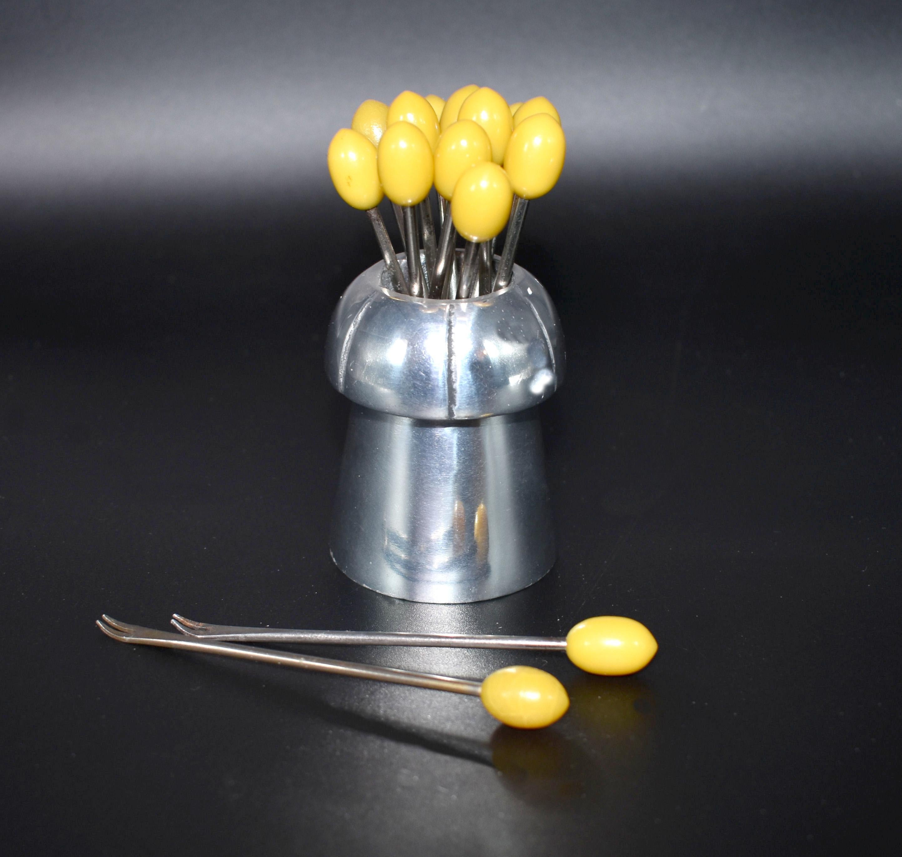 A novelty 1930s cocktail stick set originating from France. Features yellow coloured Bakelite cocktail sticks with chromed metal prongs inside a chrome pot container. Great set in very good condition, minimal signs of age, quite a rare shape.