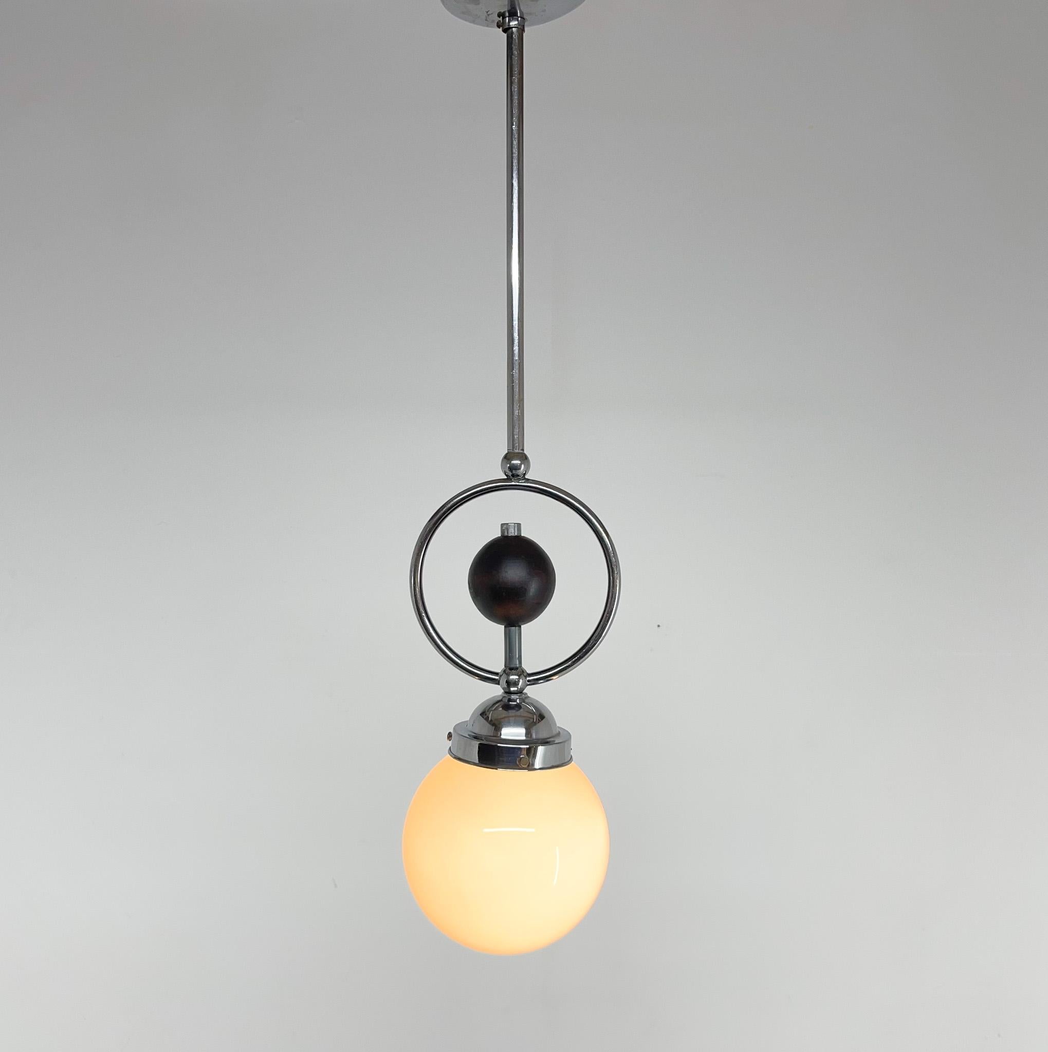 Art deco chrome and milk glass pendant light with a wooden decoration. Made in the early 1930's in Czechoslovakia.