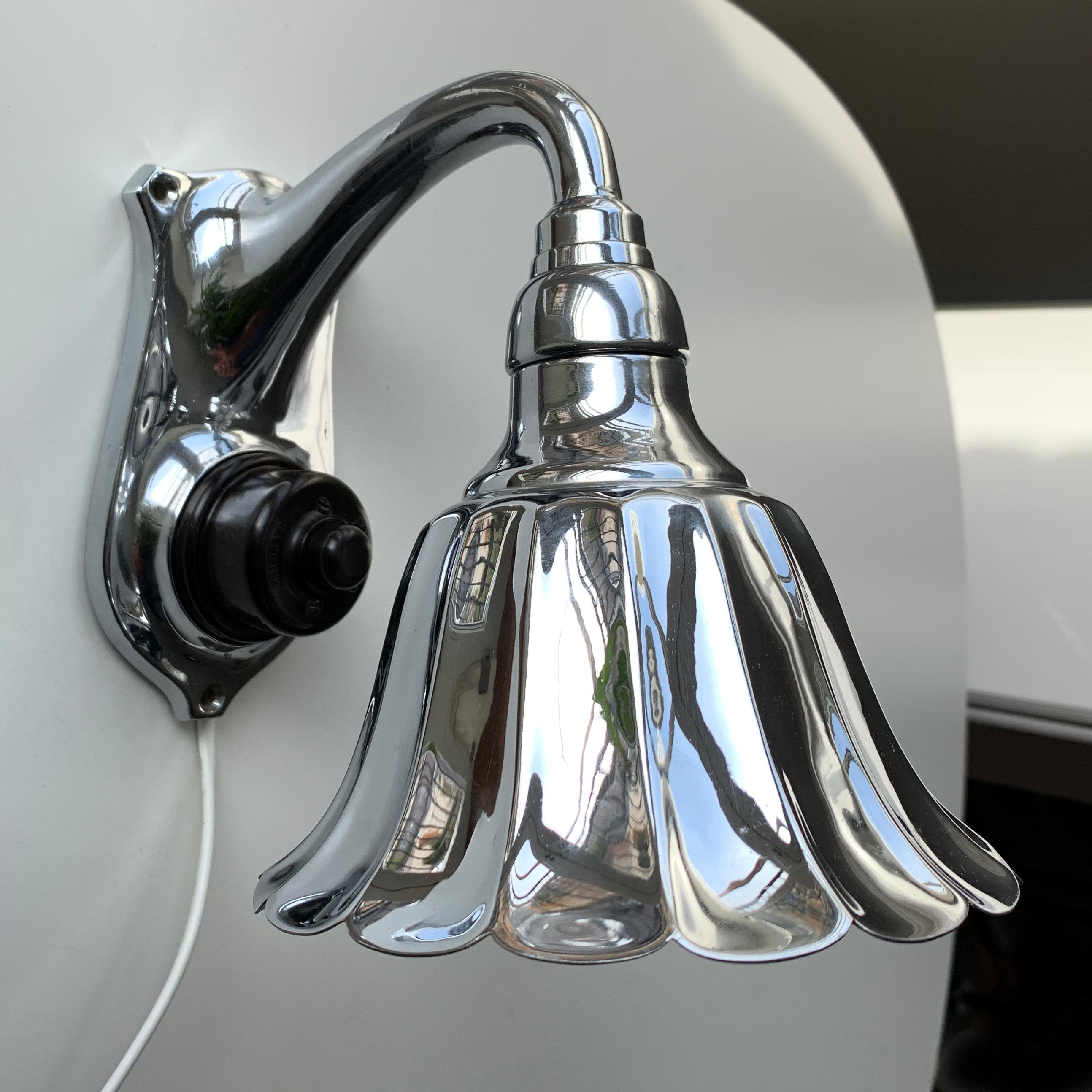 Art Deco chrome wall light with huge pello patented bakelite switch as part of the design. Chromed metal shade and base. The lamp is mounted with white cable for flexible connection. Can easily be mounted direct into wall outlet. E14 bakelite bulb