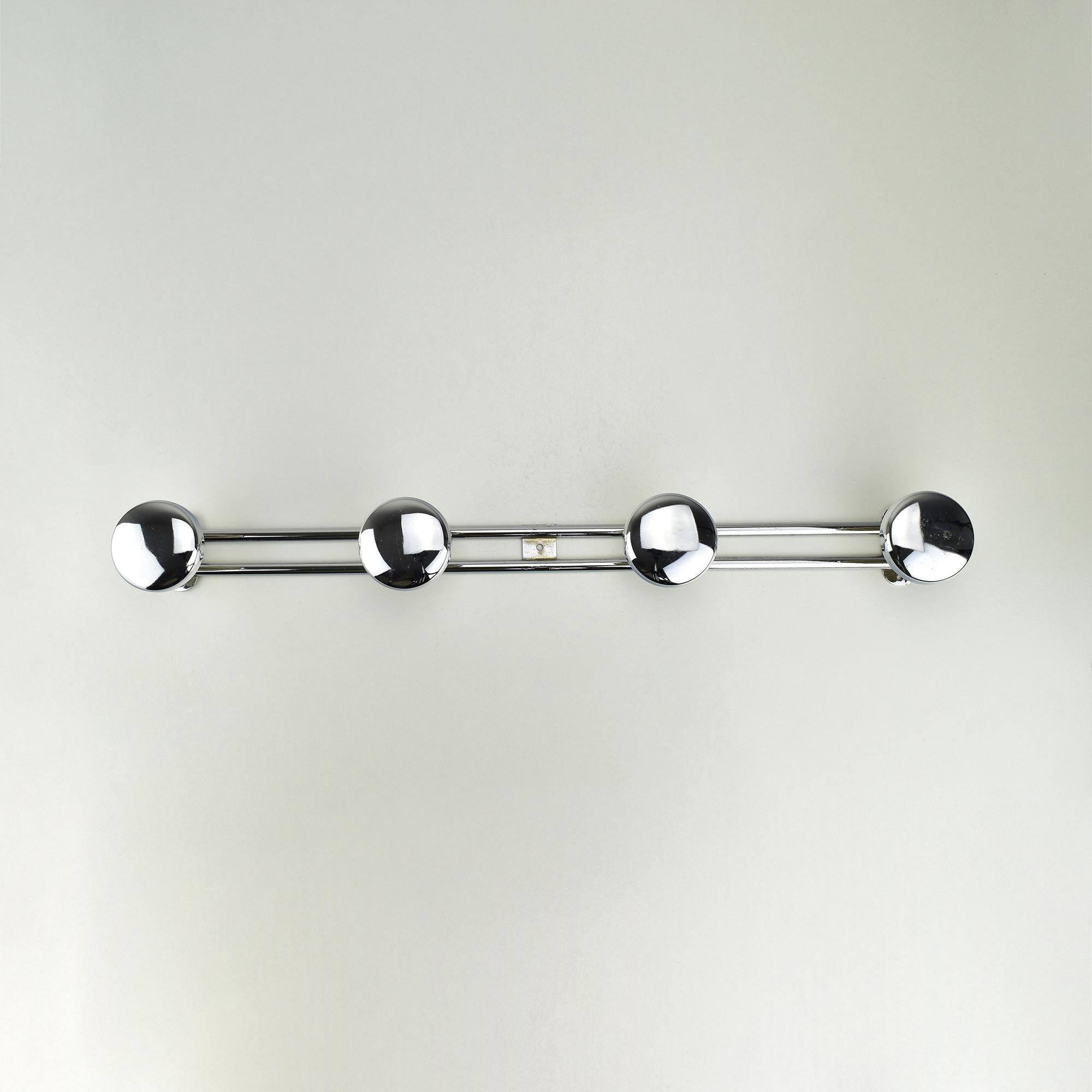 This vintage Art Deco coat rack from France, dating to the 1930s, showcases sleek chromed metal construction, reflecting the iconic streamlined design of the era. The rack features a minimalist double-bar frame supporting four round, highly polished