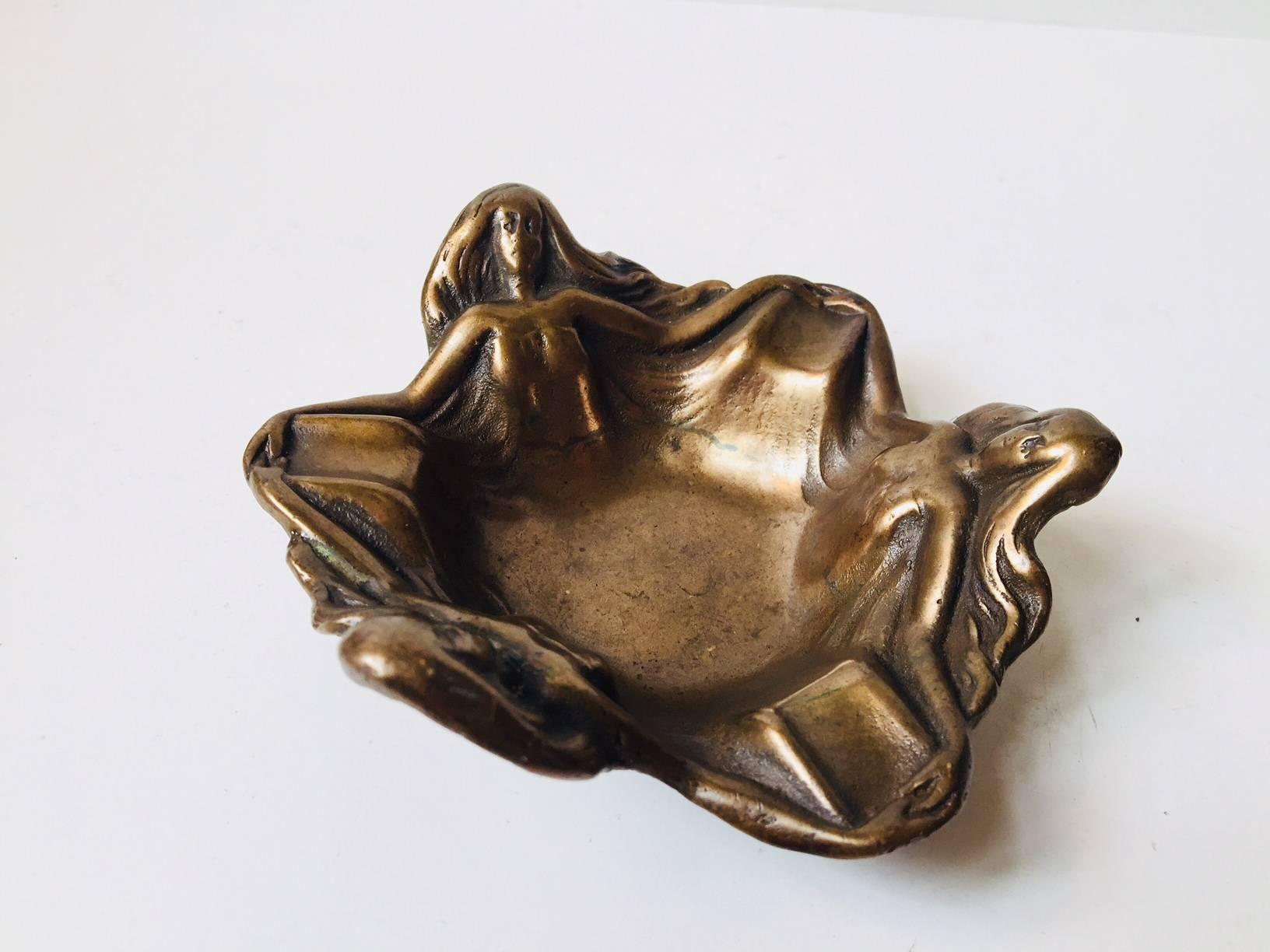 A cast brass cigar ashtray depicting three women dancing/holding hands in a circle. Manufactured in France during the 1920s or 1930s. It is richly patinated and it has seen its use. However its still intact, charming and it has another 100 years of