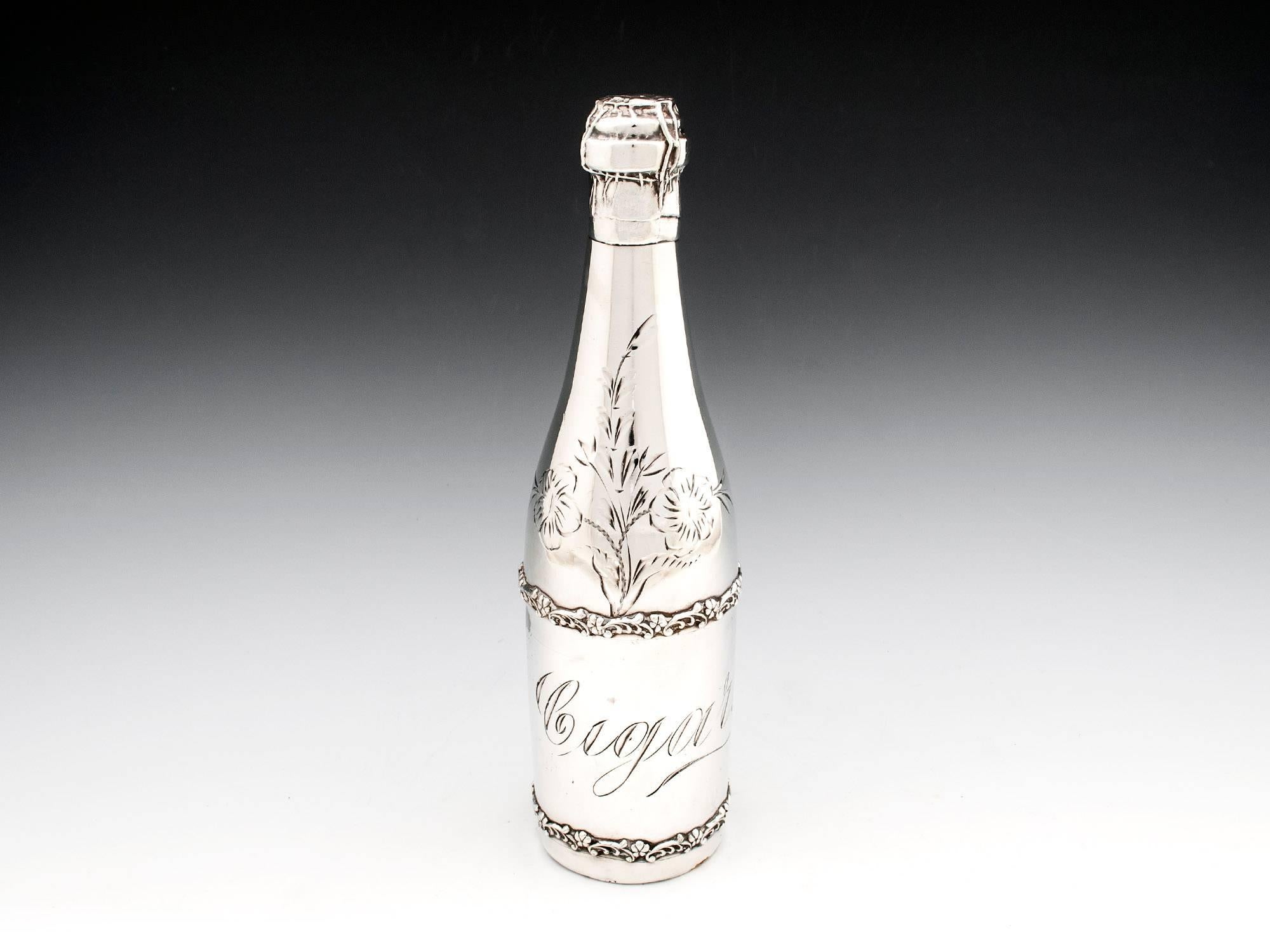 Silver plated cigar holder in the form of a champagne bottle, with wonderfully detailed top and floral bands circling the body of the bottle. 
The neck has a simplistic engraved floral design, while the body has the word 