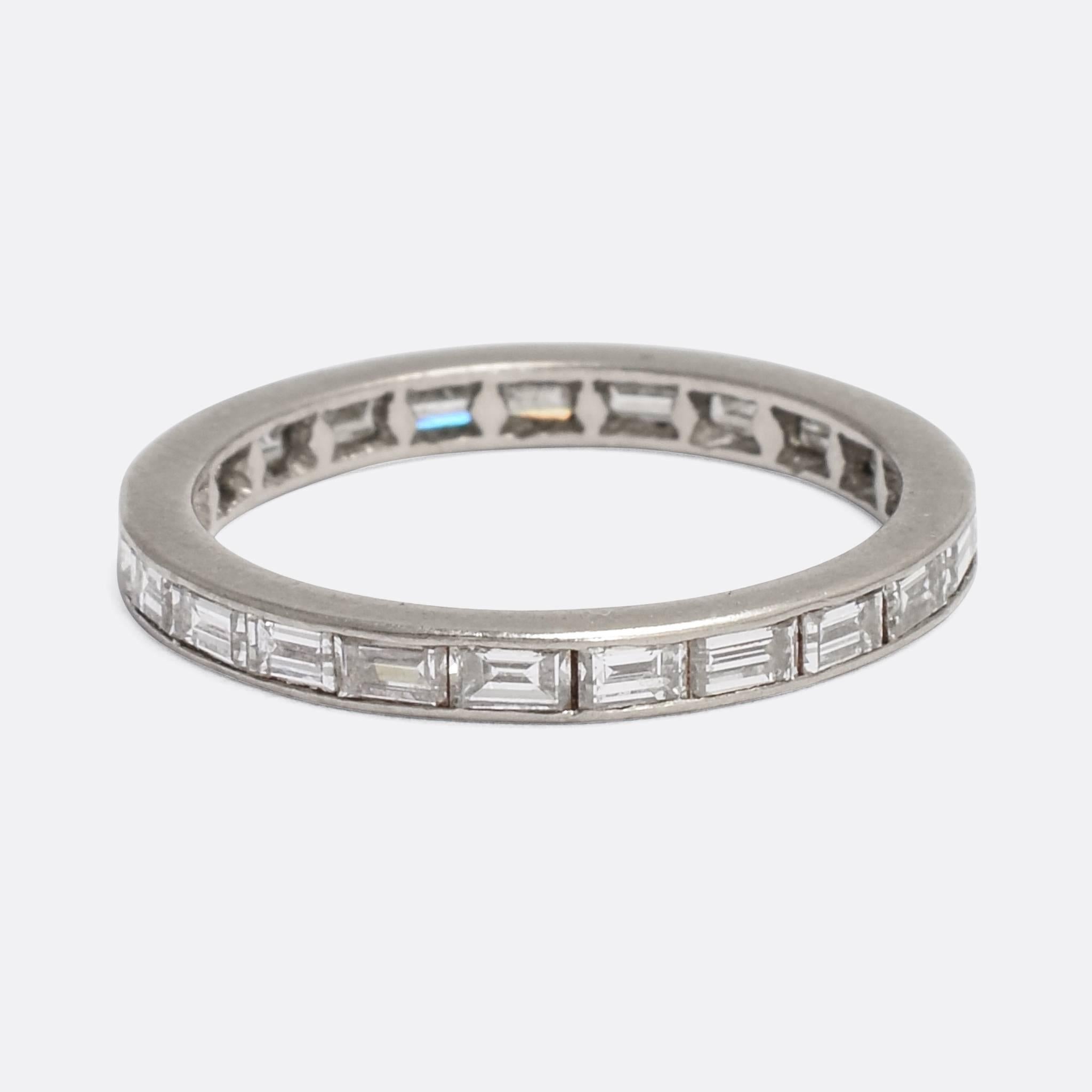 A sleek vintage eternity ring, channel set with baguette cut diamonds. It's modelled in platinum throughout, as was typical from the early 20th Century onwards, but unusually it is fully set with baguette cuts. A stylish and timeless