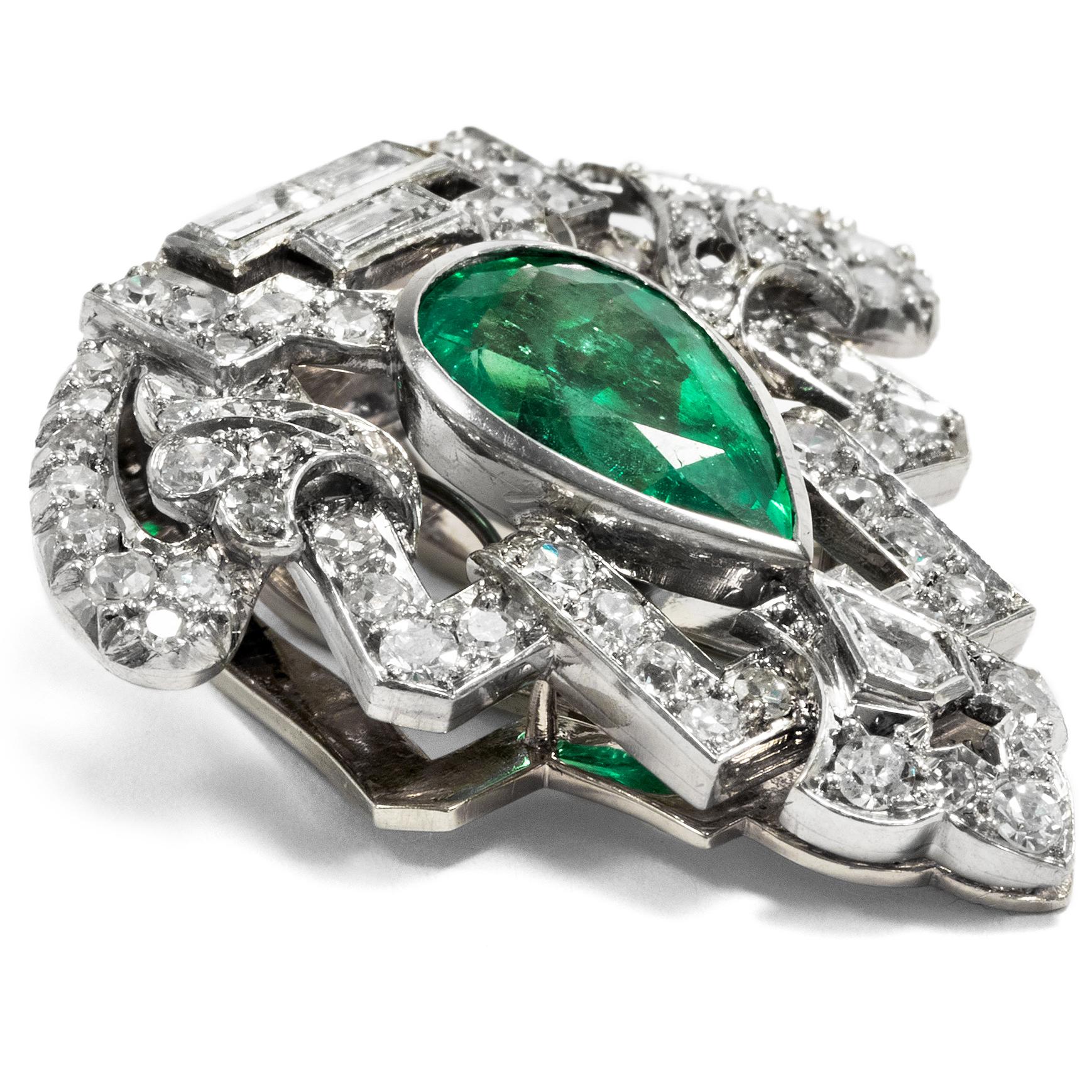 This clip brooch dates to the years around 1930 and embodies the modern spirit of the times par excellence. Gleaming diamonds and white platinum are united in an abstract triangular shape with a deep green emerald at its centre. The emerald is cut
