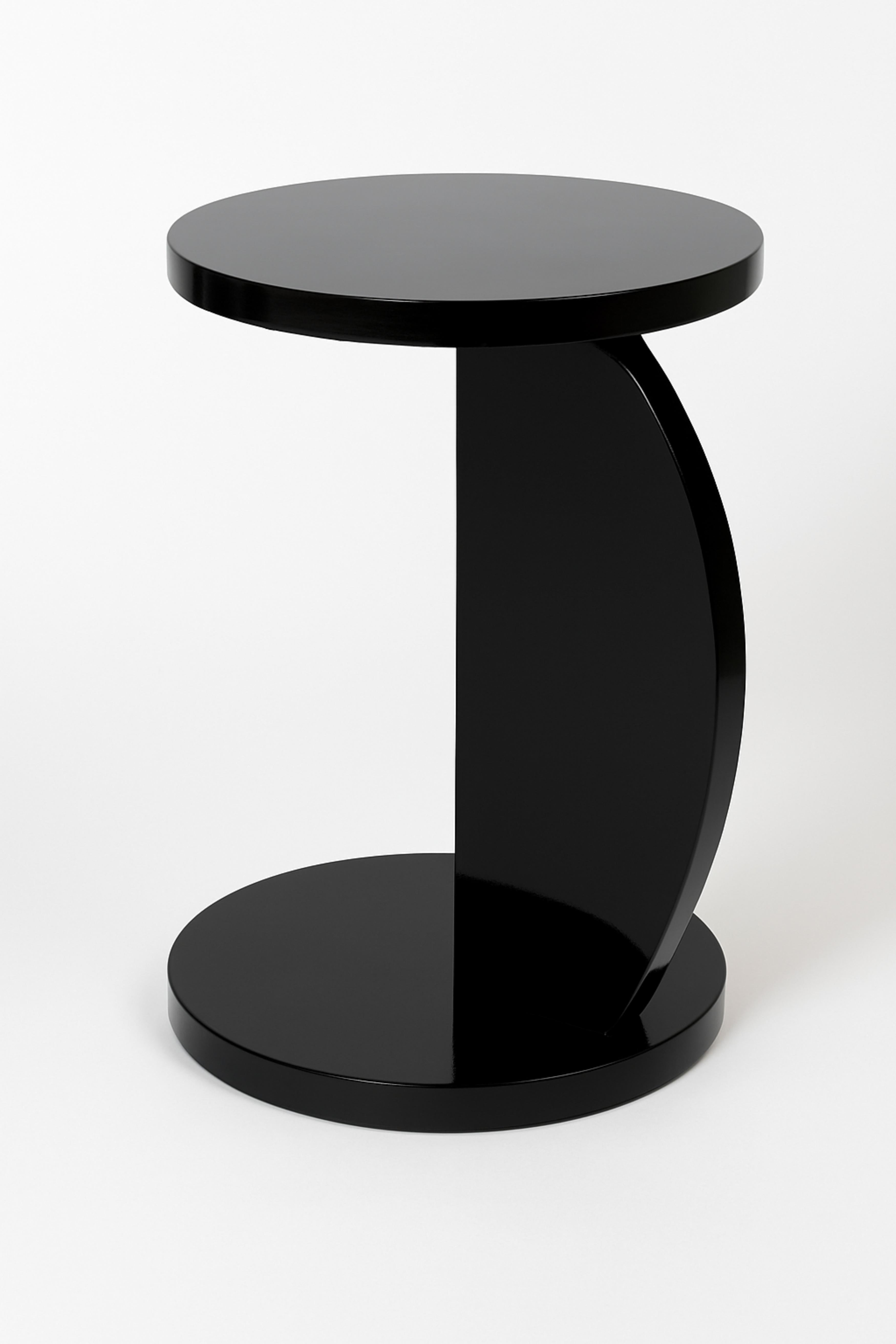 Cette table d'appoint Art Deco en forme de C couleur laque noire, a été fabriquée de manière experte en noyer. 
Il présente un design élégant et rare, avec deux plateaux circulaires lisses, l'un placé au-dessus de l'autre, soutenus par une base