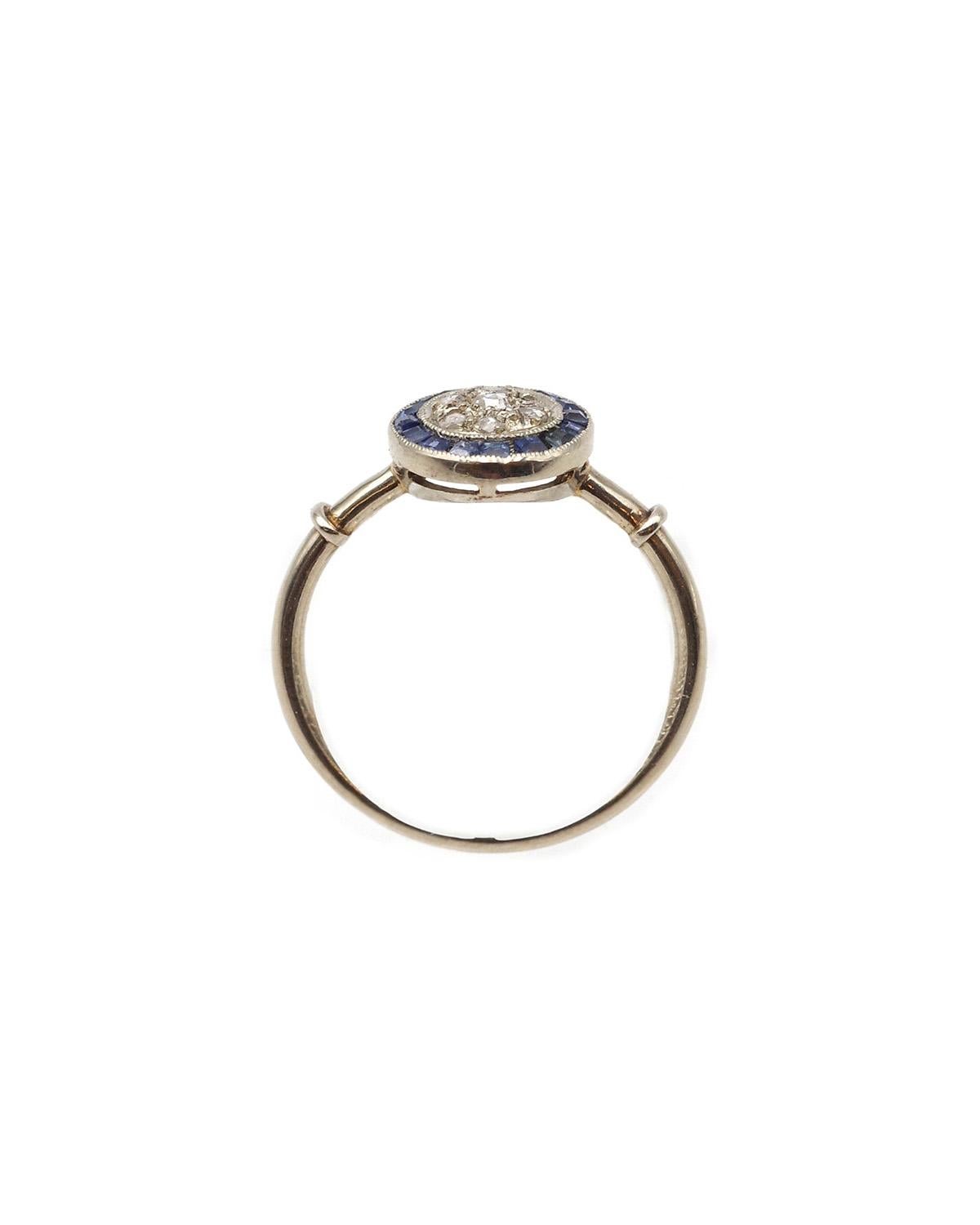 Bague saphir circulaire Art déco en or blanc 18 carats et platine. Bague circulaire Art déco sertie au centre de sept diamants taillés en rose, entourés de seize saphirs naturels calibrés bleu ciel. L'anneau est élégamment décoré de deux godrons sur