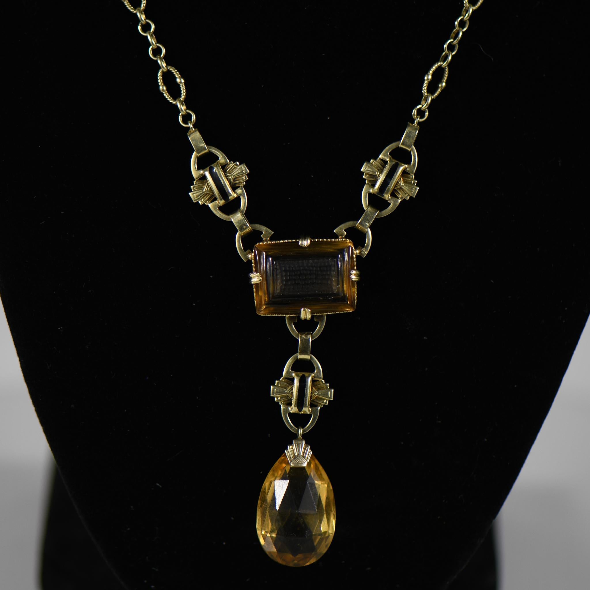 Crafted in the opulent style of Art Deco, this exquisite citrine necklace exudes timeless elegance. The centerpiece features a stunning portrait-cut citrine, meticulously carved to capture intricate details and depth, evoking a sense of