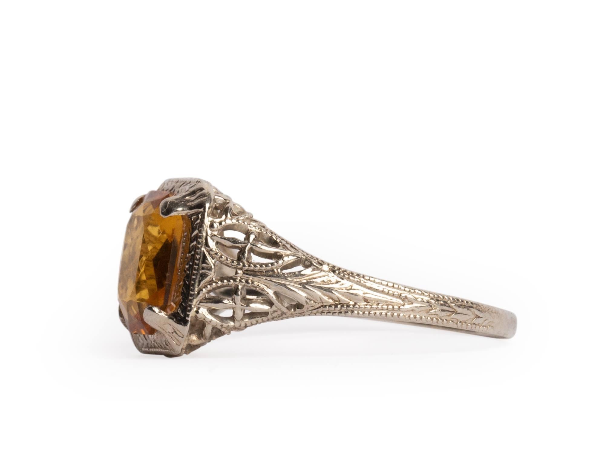 This piece is crafted of 14K white gold featuring intricate filigree and carved details that cascade down the shoulders complimenting the center gem perfectly. The center is a  beautiful amber colored citrine in a radiant cut. The color of the