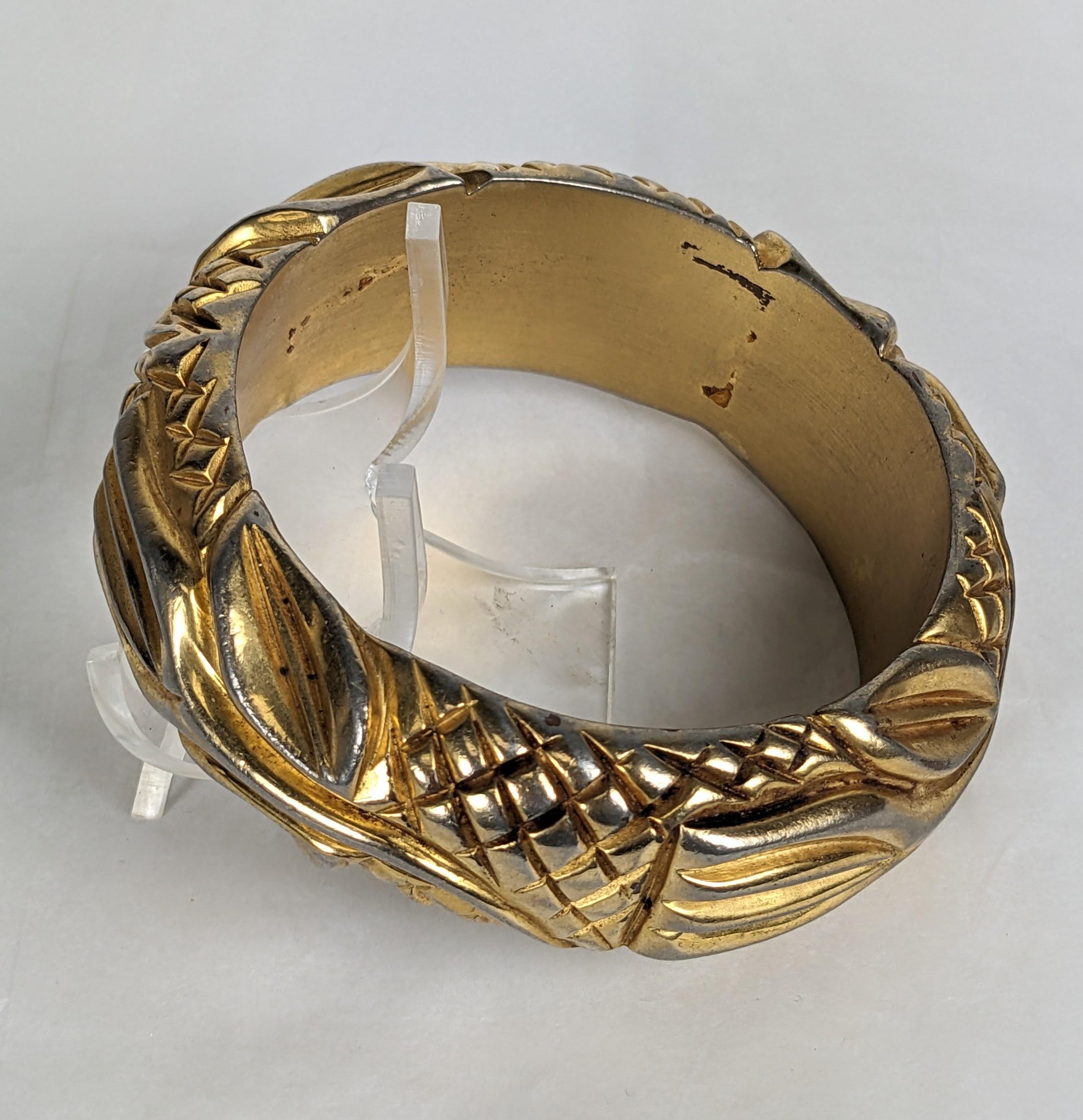 Insolite bracelet Art déco en bakélite plaquée et dorée des années 1930. Sculptée de motifs Art déco en forme de tulipe et de hachures, elle est ensuite 