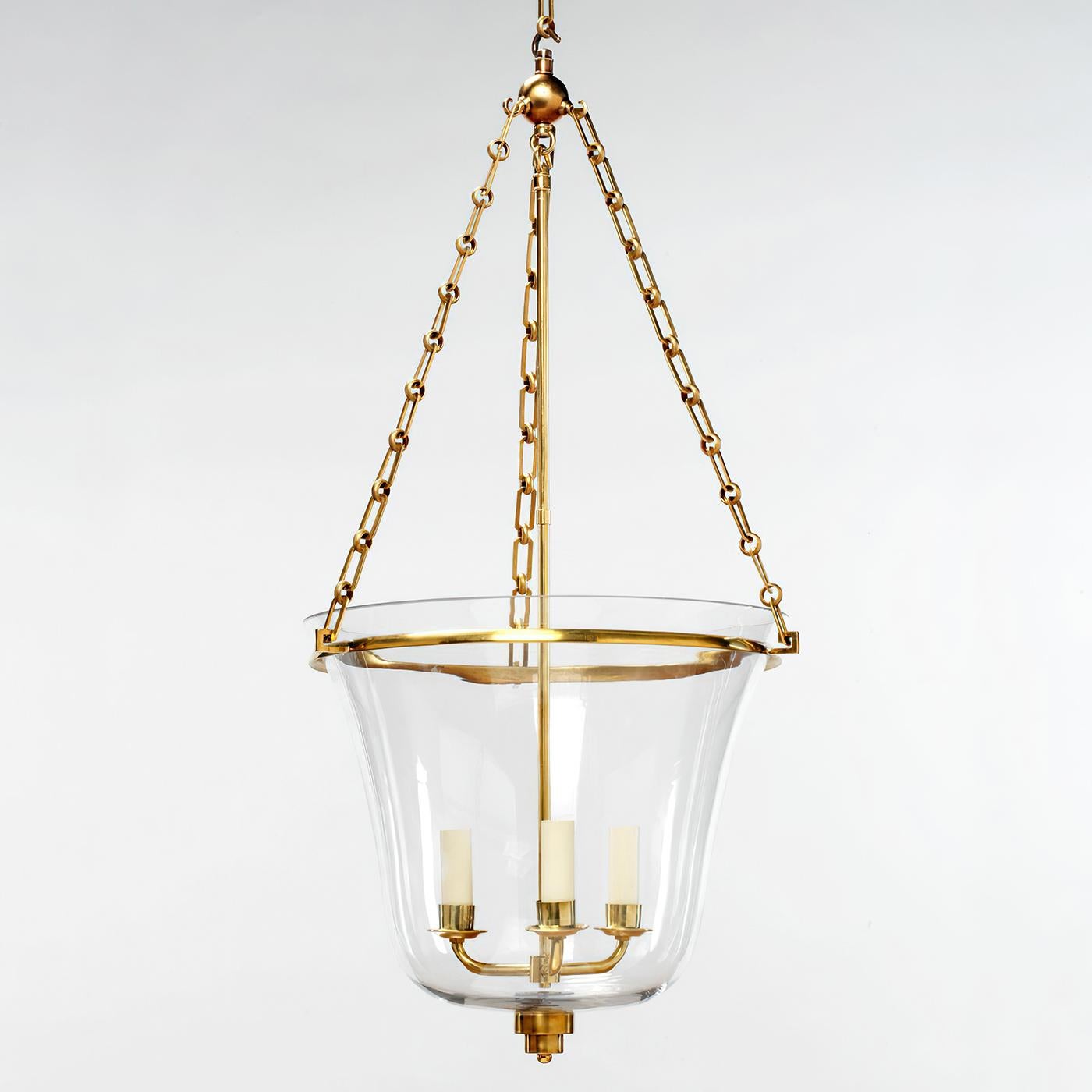 This design features a graceful hand-blown glass bell. The glass is paired with a sleek cast brass circular band and Art Deco style finial. The lantern has a solid cast brass frame and decorative components.

The close-up shows the hand-blown