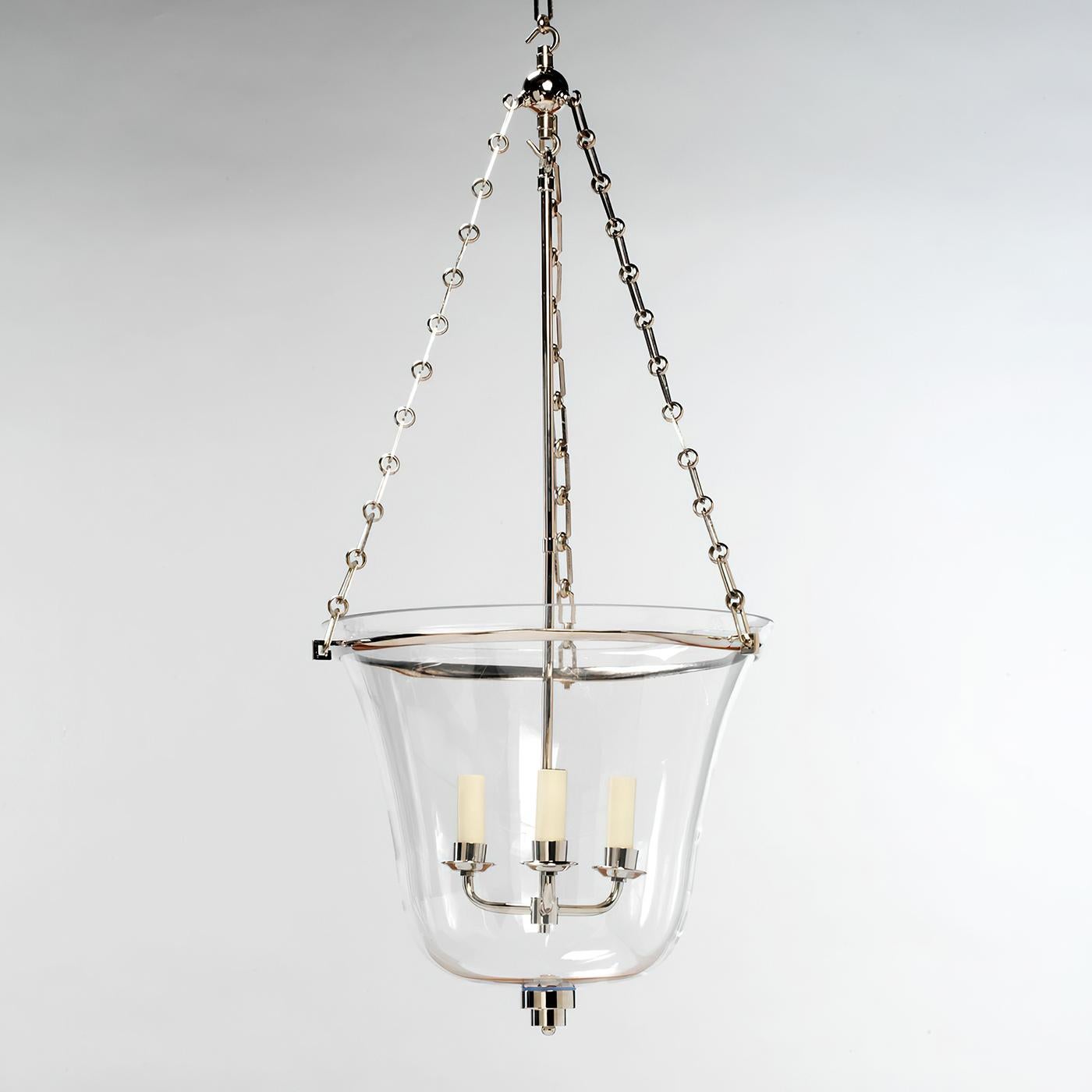 This design features a graceful hand-blown glass bell. The glass is paired with a sleek nickel-plated cast brass circular band and Art Deco style finial. The lantern has a solid cast brass frame and decorative components which are then nickel