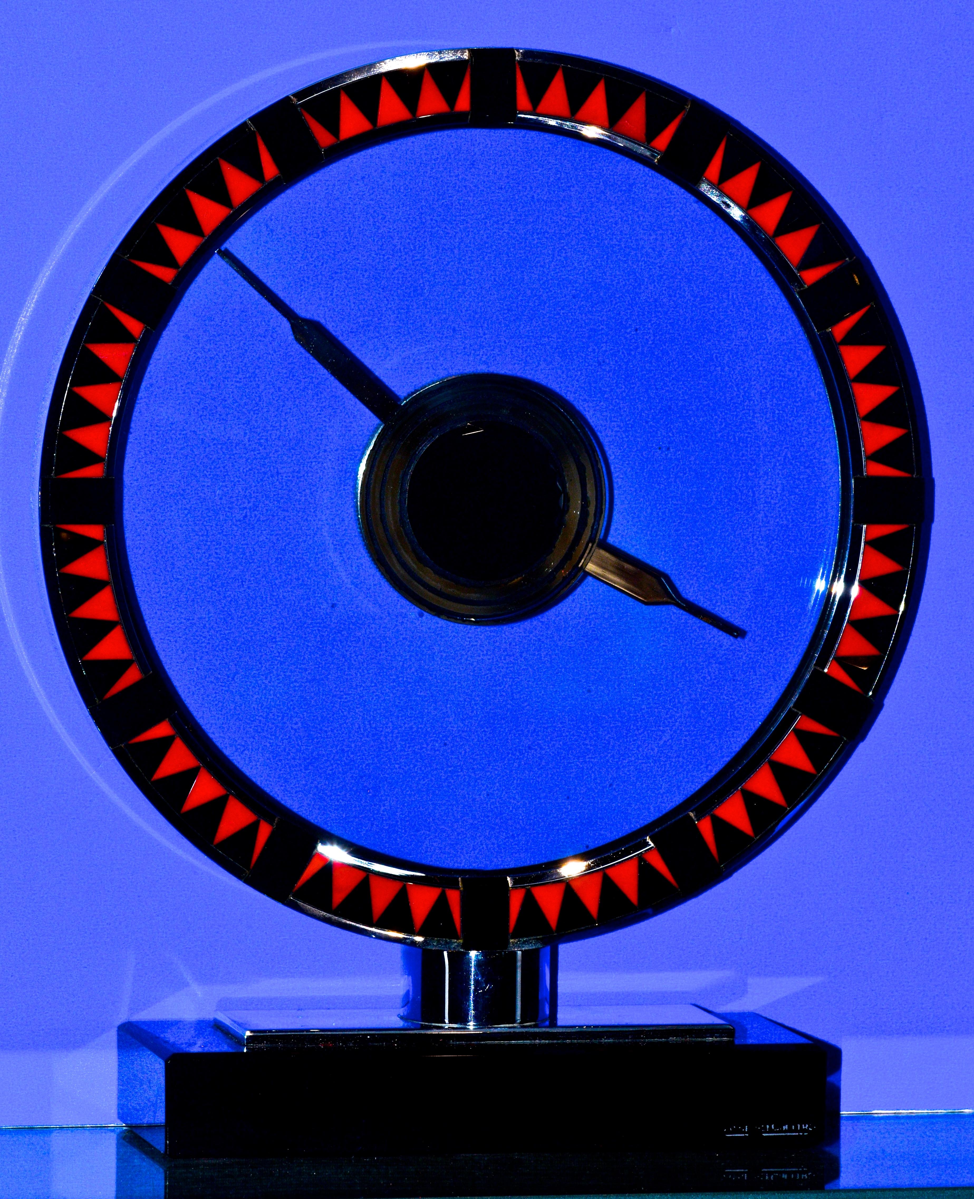 Jaeger LeCoultre Art Deco clock measuring 8 5/8th by 7 1/8th inches, this is likely a one and only example of an Art Deco clock in polished stainless steel, with faceted pyramidal triangular onyx alternating with vivid red (not orange), triangular