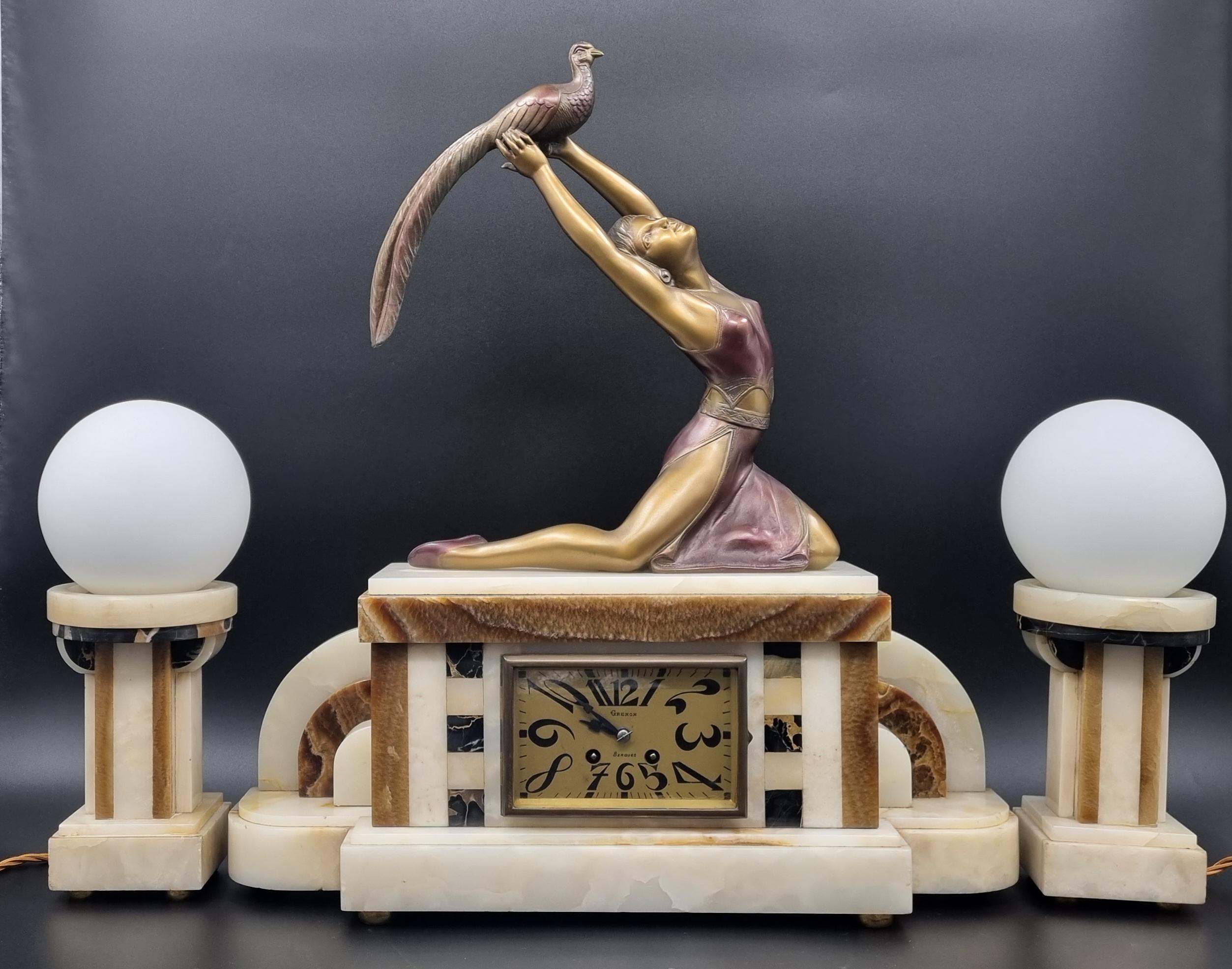 An extremely rare Art Deco clock set with a pair of lamps, topped with a spelter statue of Art Deco lady holding a bird, signed at the back of the spelter 