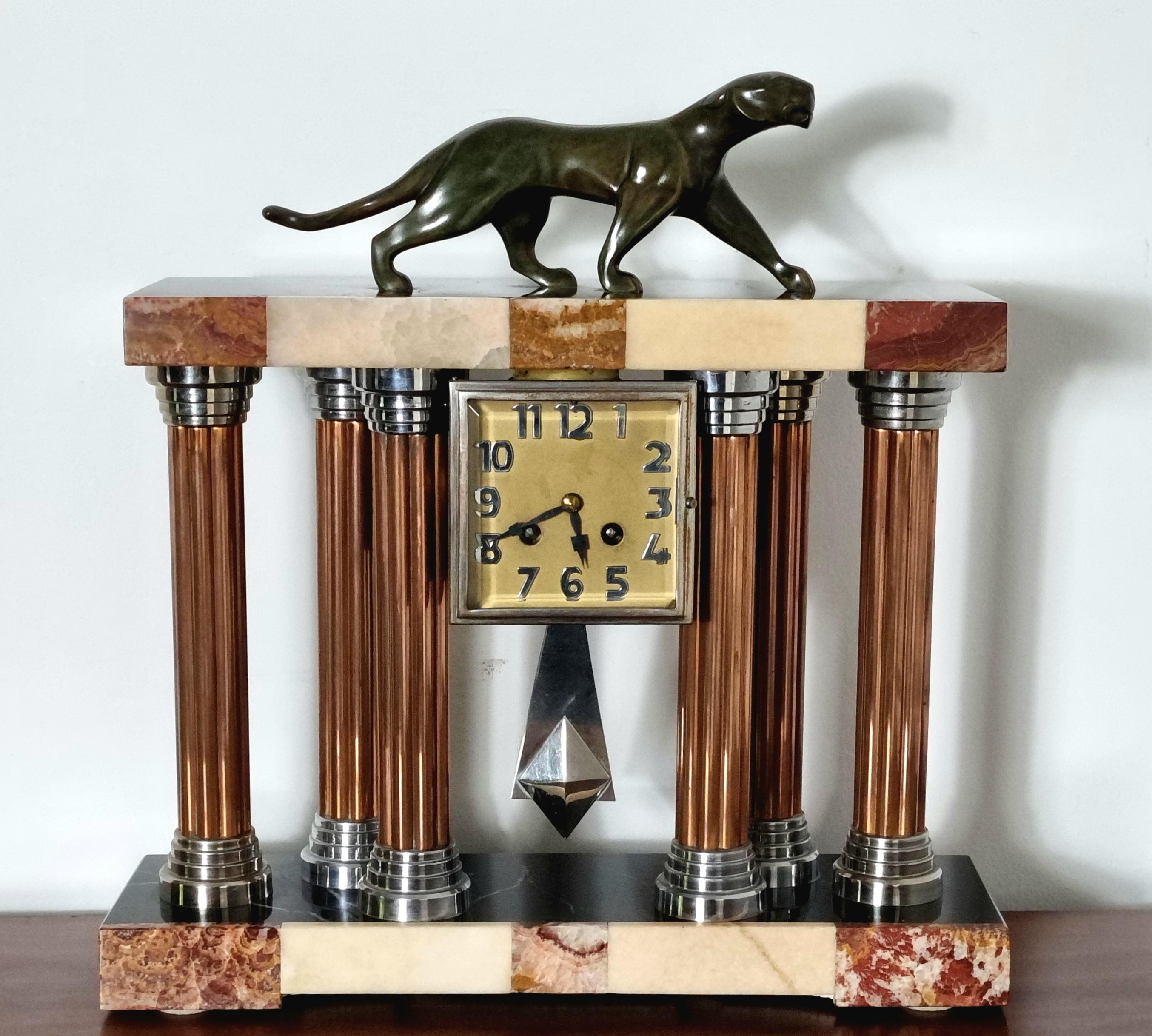 An iconic Art Deco clock made by the renowned artist of Art Deco period, Michel Decoux. This exceptional piece boasts a highly decorative clock case, expertly crafted from rich marble and onyx, supported by sleek chromed and copper pillars. At the