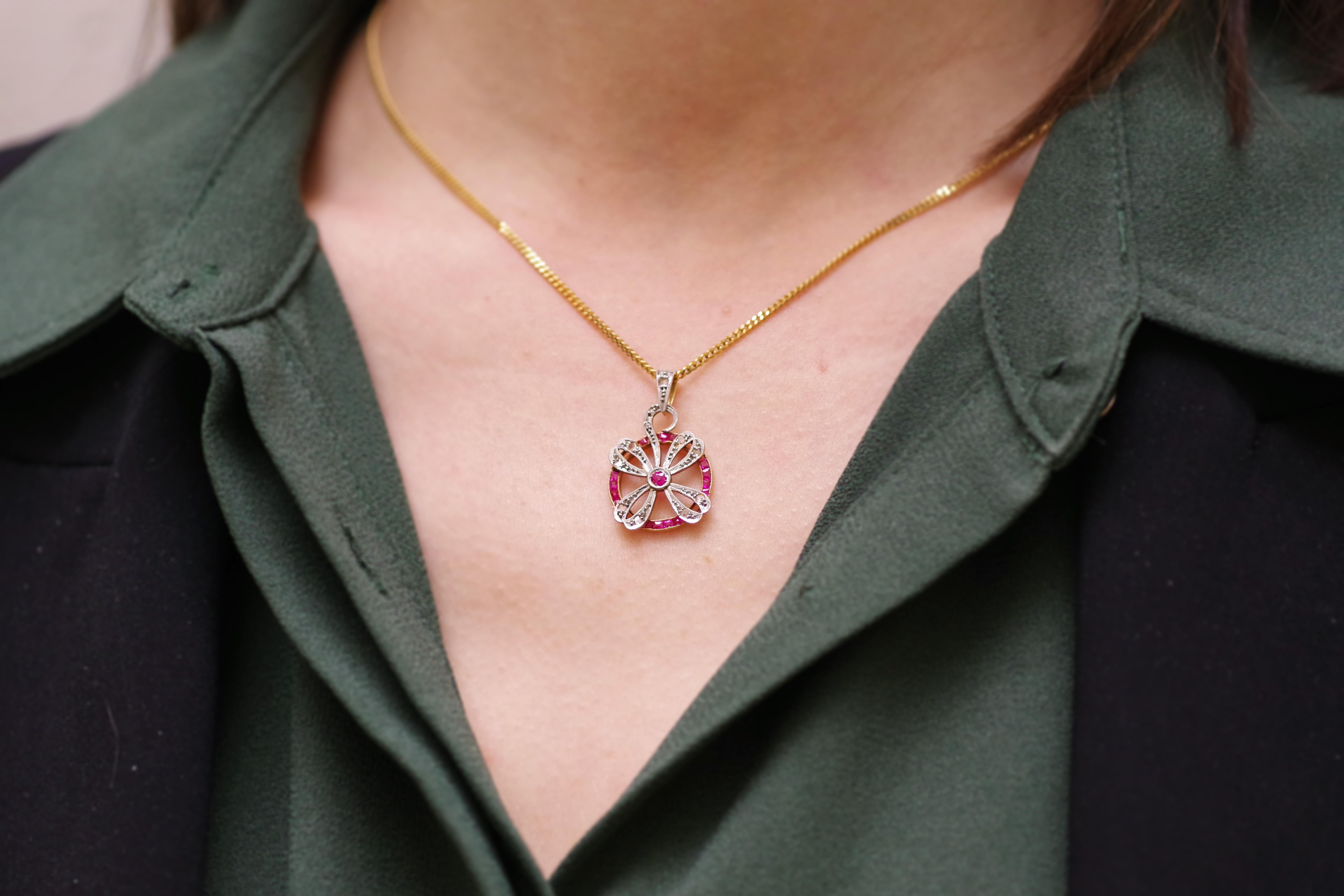 Art Deco clover ruby pendant in platinum and 18-karat rose gold. A lucky four-leaf clover pendant in platinum set with eight rose-cut diamonds. The clover is centered by a round synthetic ruby and encircled by calibrated synthetic rubies. The
