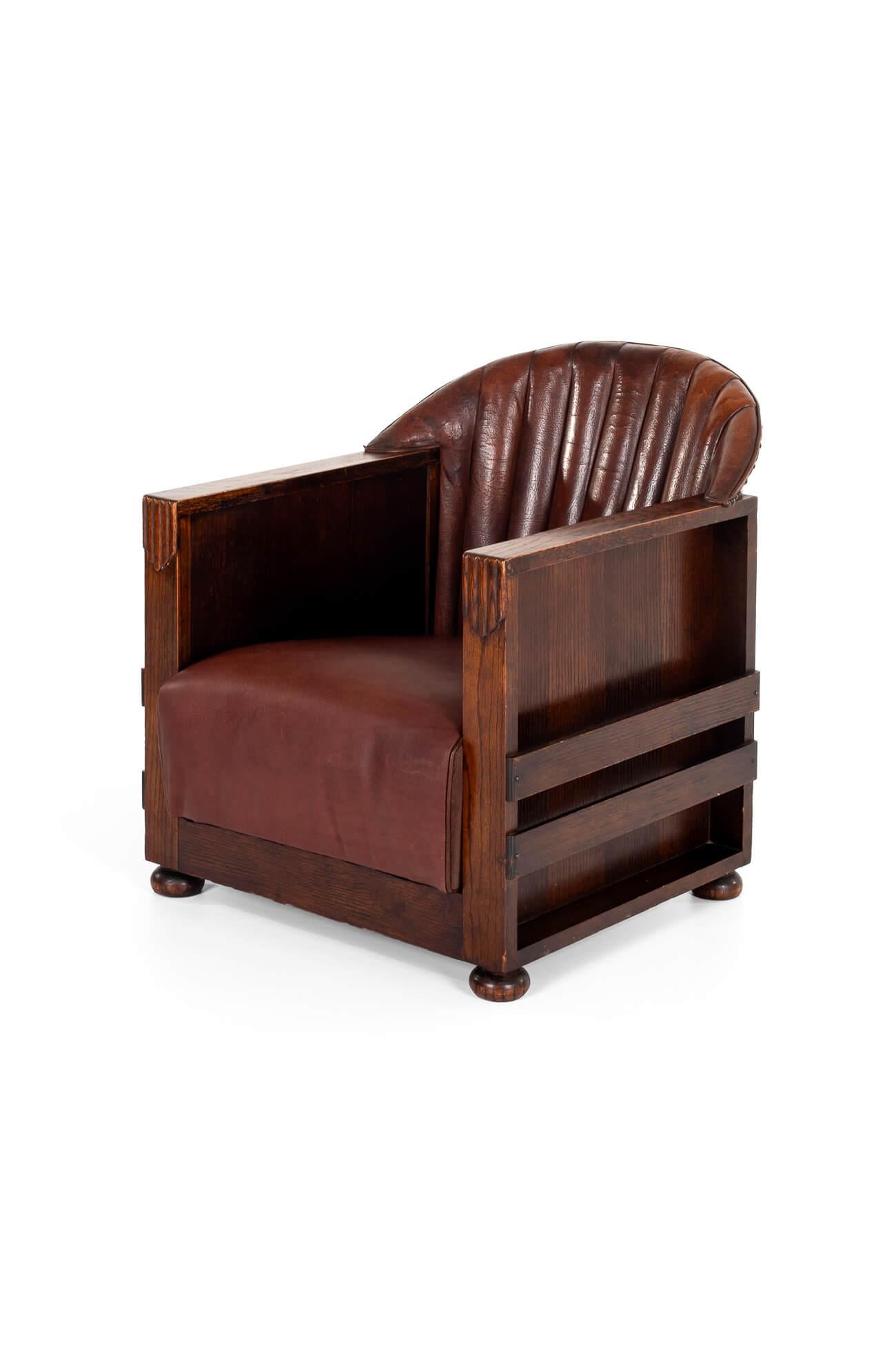 A rare and unusual English Art Deco aviator-style club chair in oak.

The supple cognac leather fluted back complements the generous leather hide spring box seat. The box arms have symmetrical decorations of the period and are all raised on oak bun