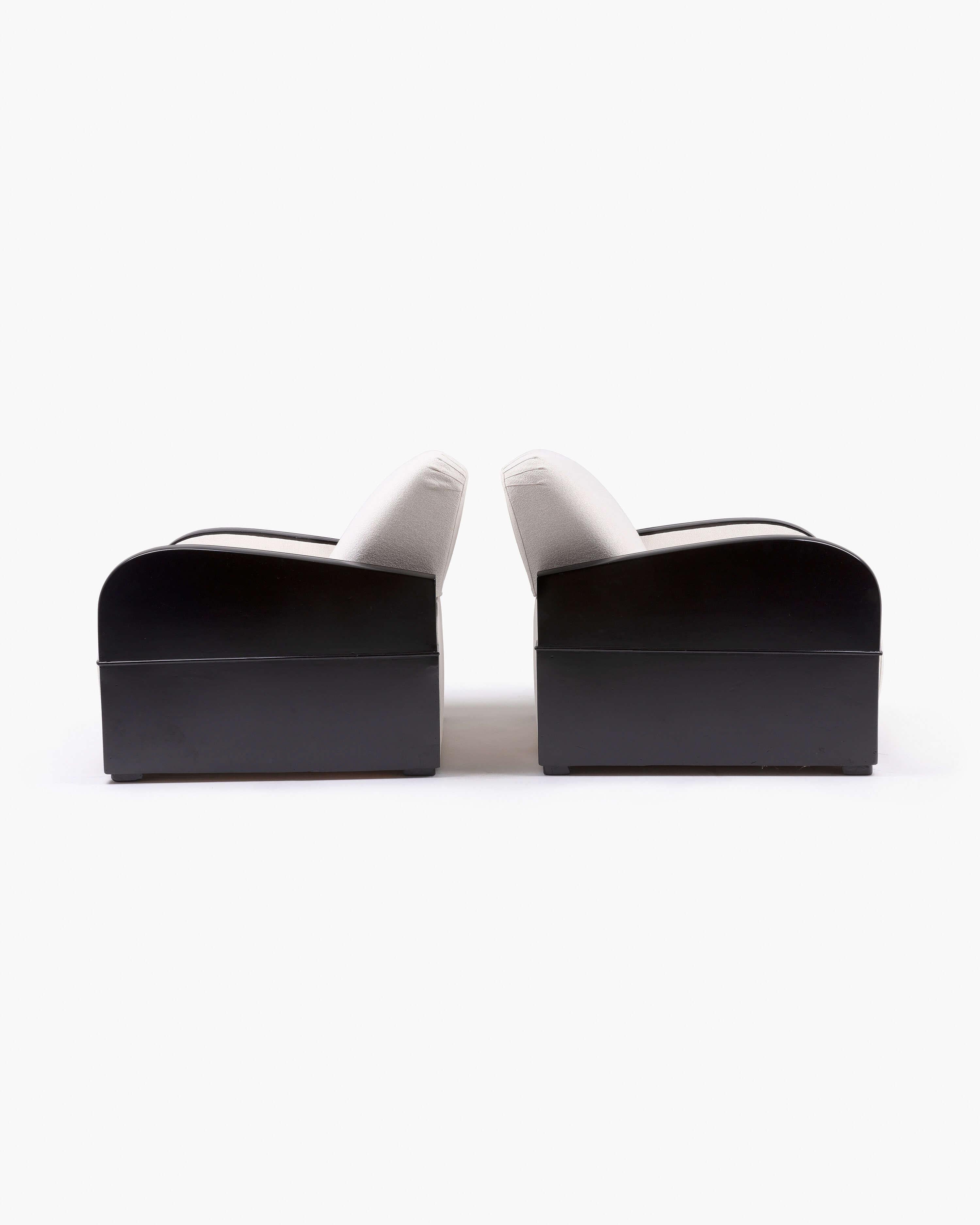 This pair of black lacquered armchairs features plush white bouclé cushioning. High-gloss features are softened slightly by the tufted upholstery to create a luxurious yet cozy set of club chairs—a perfect feature for any thoughtfully curated living