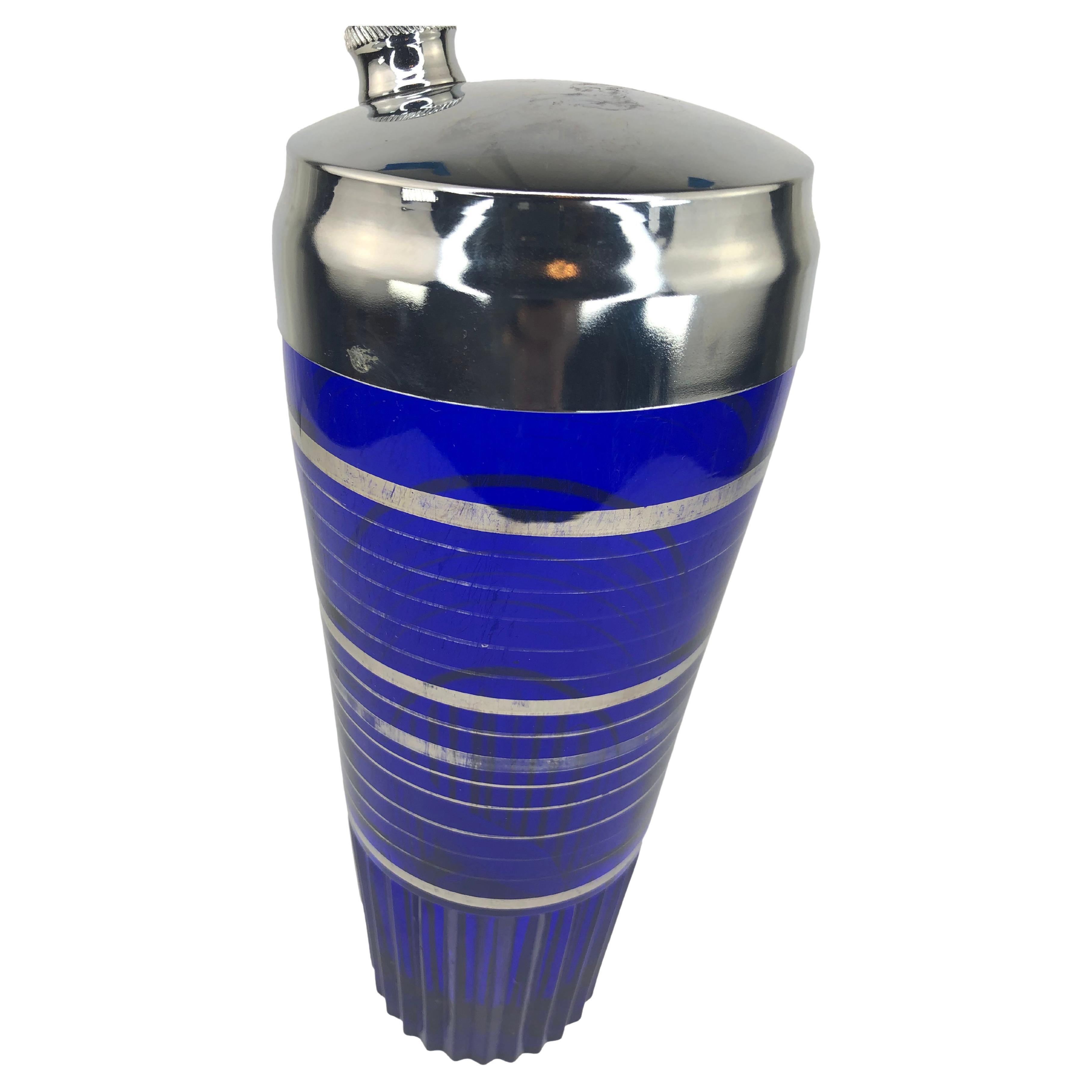 Art Deco Cobalt Blue Cocktail Shaker With Silver Overlay Bands and Fluted Base. Shaker has a small chip at the base, shown in photos. Diameter measurement of 3.5