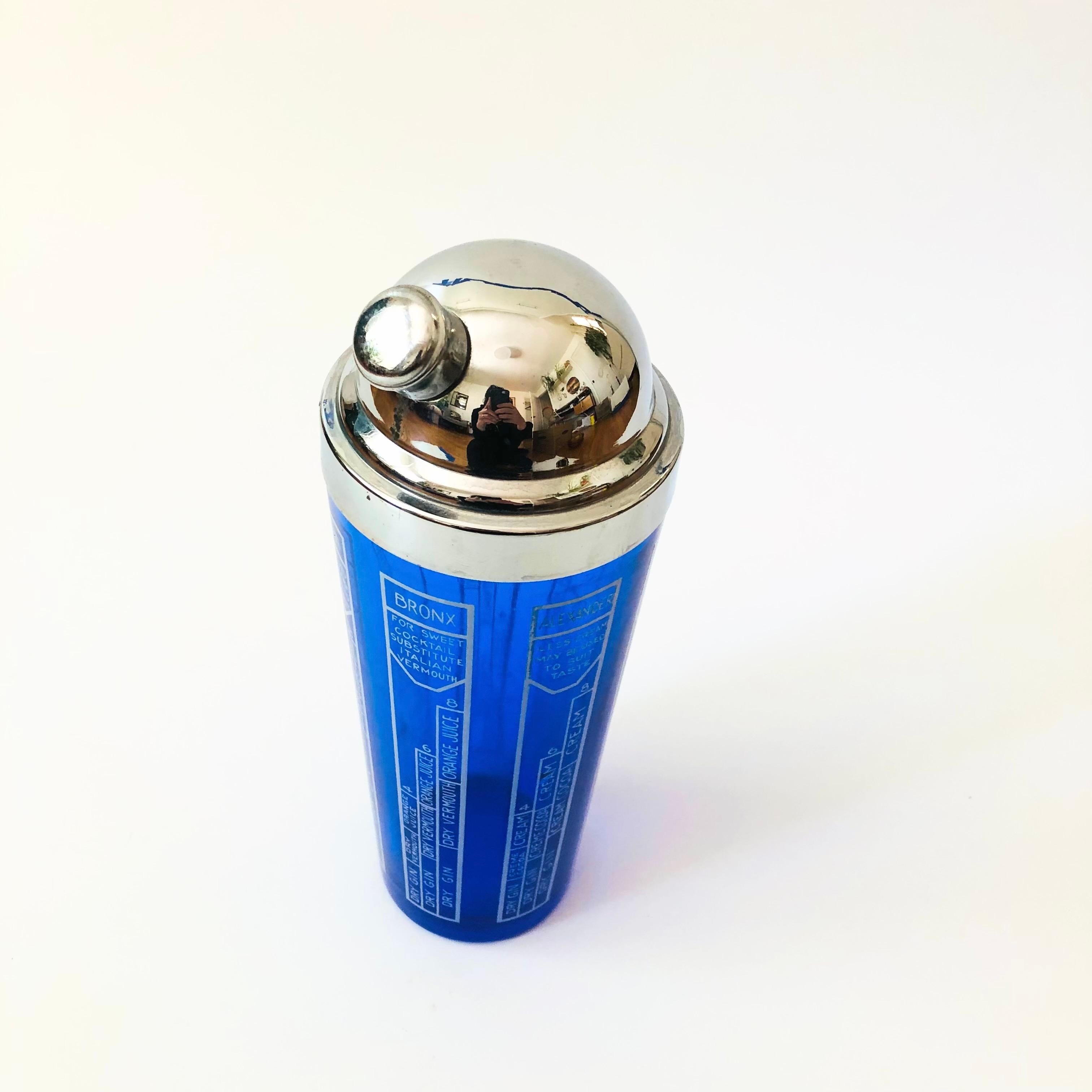 Uno shaker da cocktail in vetro Art Deco vintage. Il bicchiere è di un vibrante colore blu cobalto ed è decorato ai lati con varie ricette di cocktail classici. Il tutto completato da un CAP cromato.


