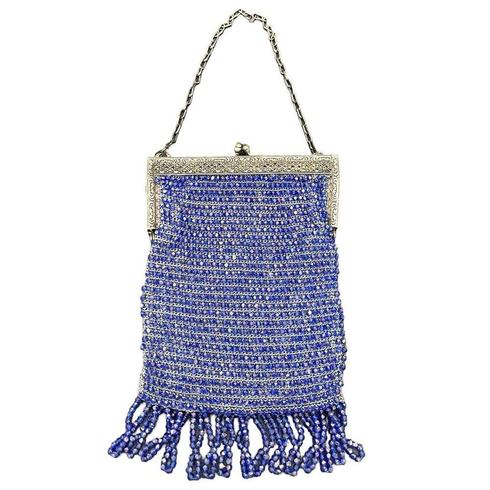 The handbag features intricate silver Art Deco clasps adorned with delicate floral etchings, showcasing the era’s emphasis on refined, geometric-inspired details and a cobalt blue glass seed-beaded exterior. The bag’s interior is lined with a soft,