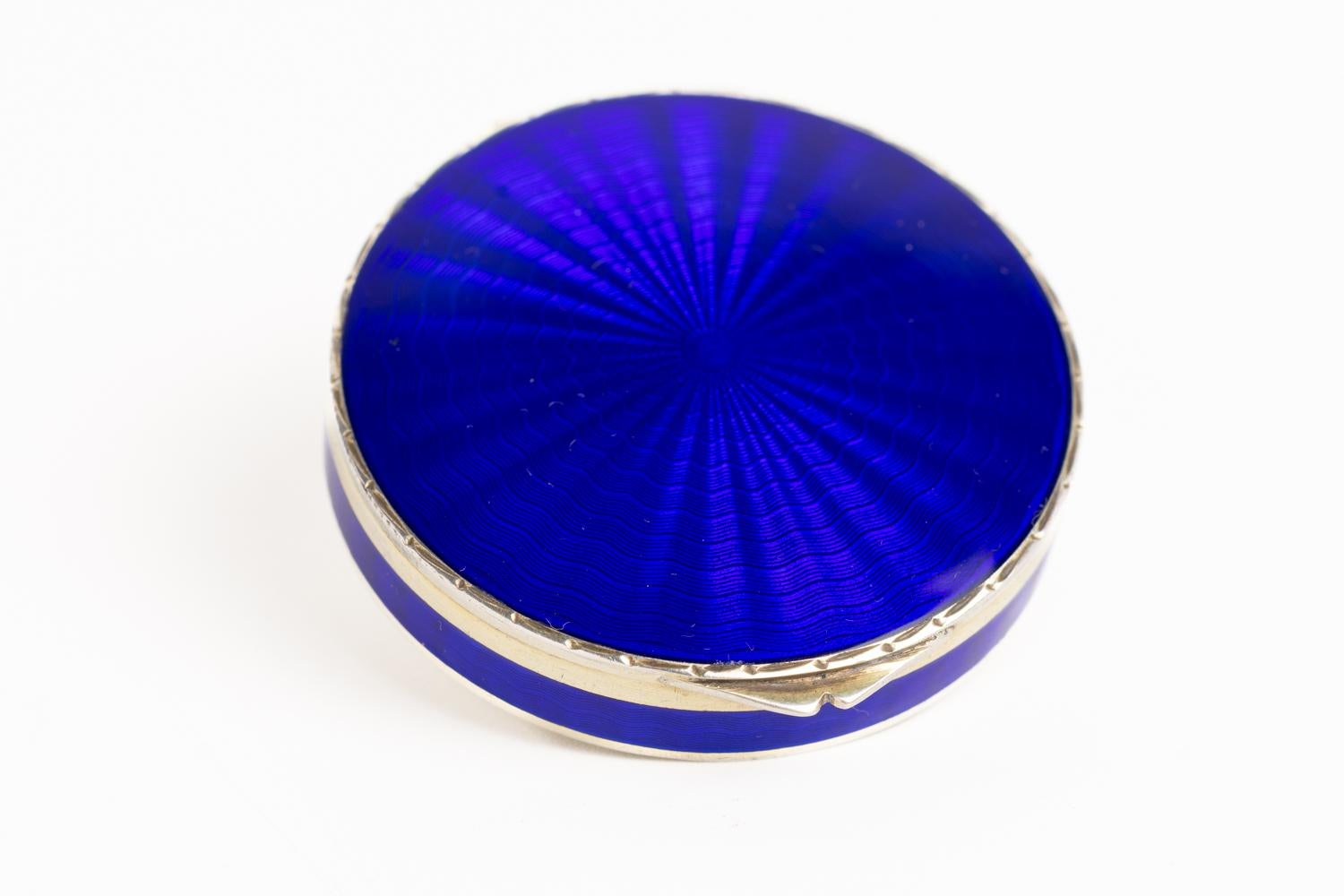 This Art Deco 1920's Cobalt Blue guilloche enamel and silver gilt mirror compact is most likely made in Switzerland. The front cover of this unique piece is decorated in a striking cobalt blue guilloche enamel with a circular design that gives an