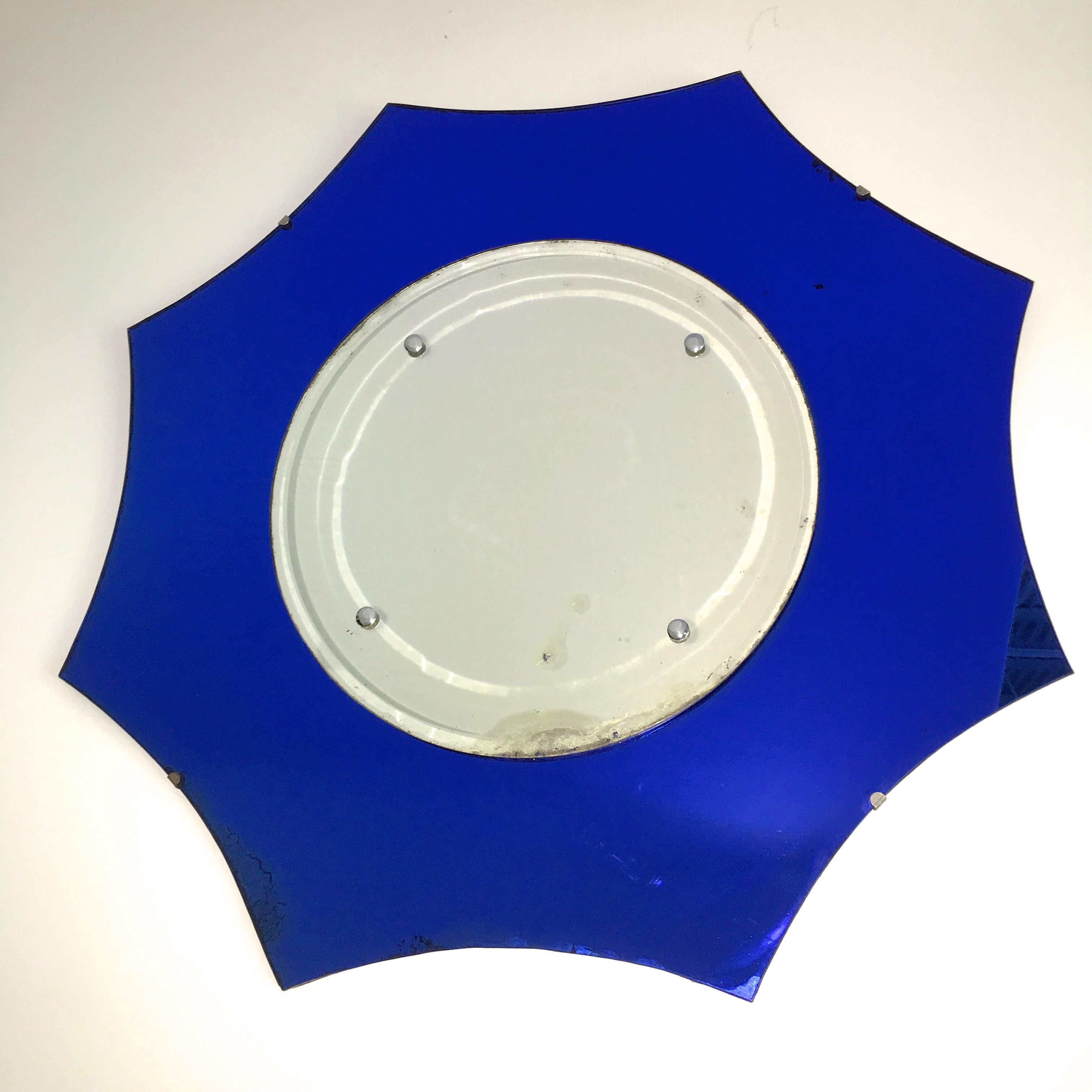 1930s American star pointed midnight blue glass mirror with round beveled glass silver mirror applied on center with four chromed cap fittings, clipped to thin wood back. Most likely Tufflex glass, then a division of Libbey Owens Ford and used by