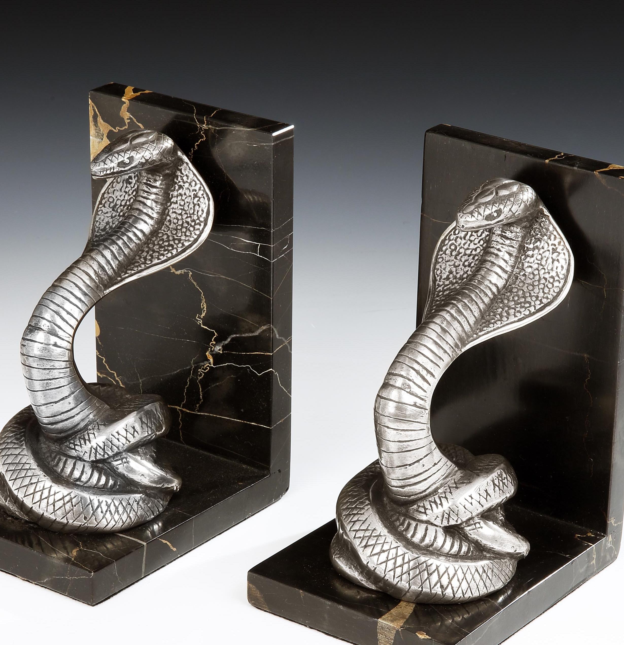 Irénée Rochard (French, 1906-1984)

A pair of incredibly stylish Art Deco bookends in the form of King Cobras, the detailed snakes in patinated bronze, are shown in a striking position, and set on portoro nero marble bases, French, circa 1930.