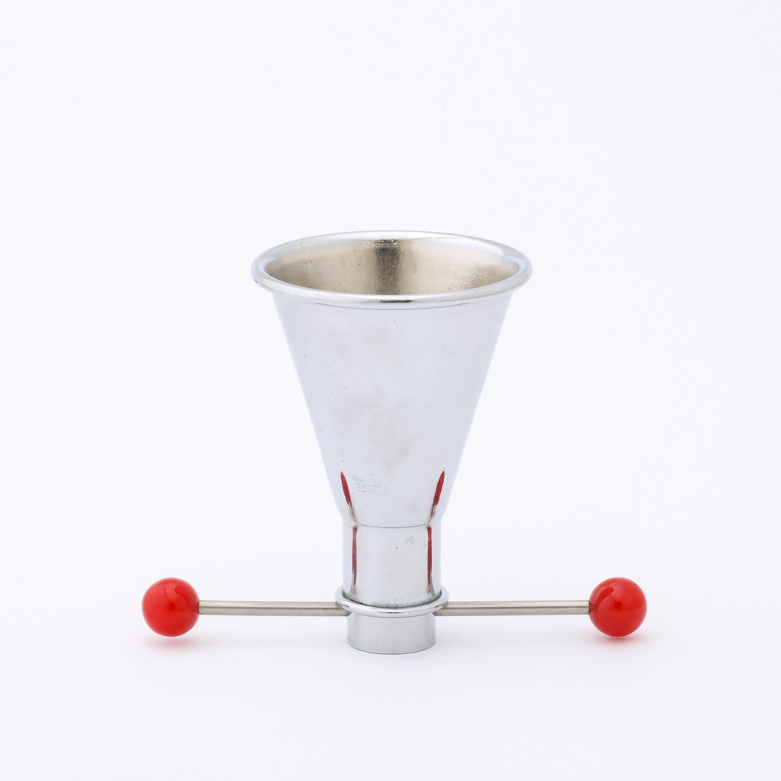 A beautiful and functional Art Deco Cocktail Jigger in Chrome with Red Bakelite detailing, this piece originates from the United States Circa 1930. The conical form is fabricated in Polished Chrome with two spheres of Candy Red Bakelite. Its cross