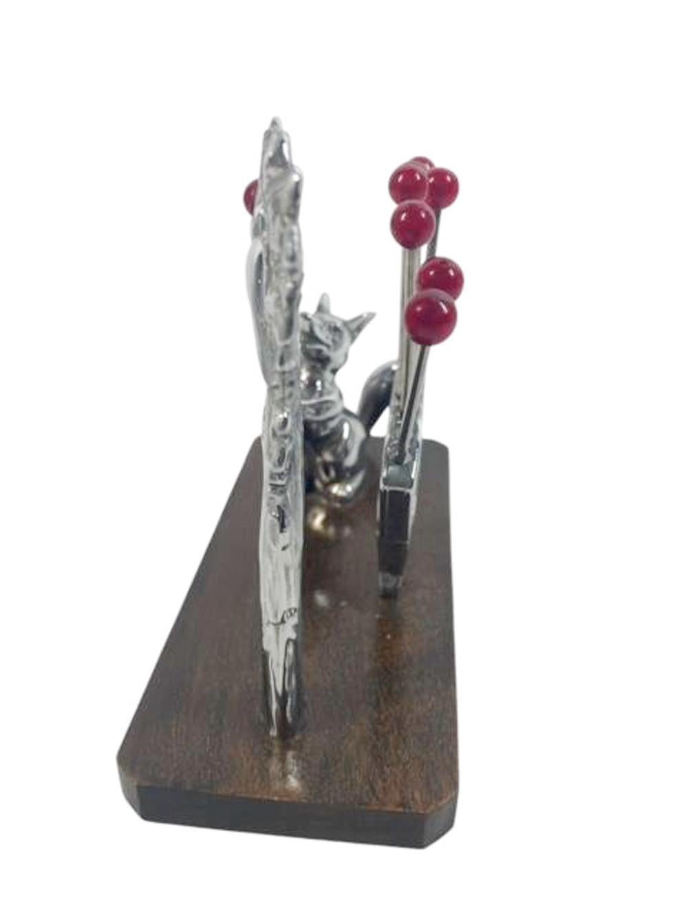 An Art Deco cocktail pick set based on the fable of The Fox and The Grapes, with red berry topped picks held high in a fan shaped trellis out of the reach of a fox who is watching a bird sitting in a tree with a berry in its mouth. In the fable the