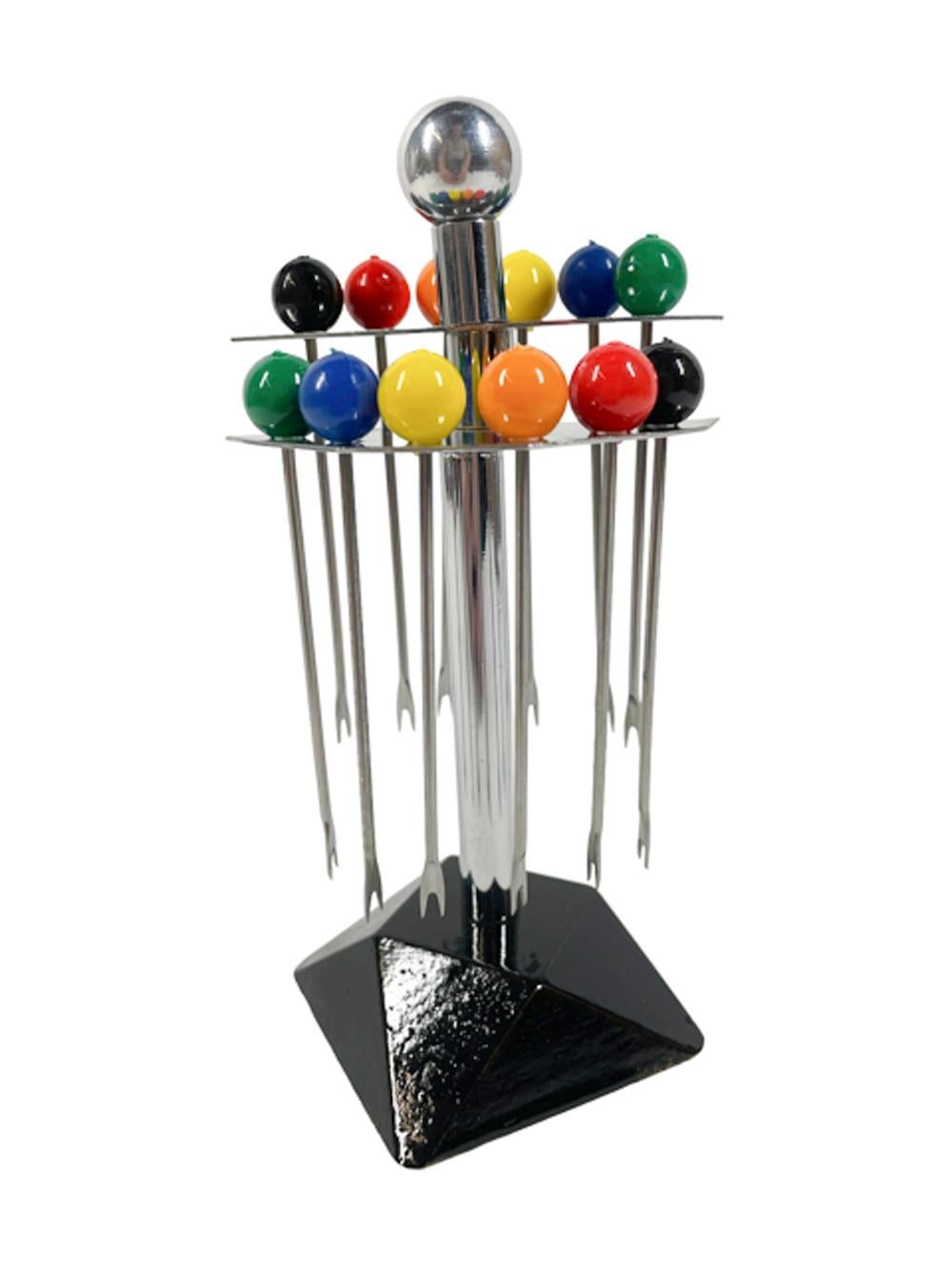 Set of 12 Art Deco Bakelite topped cocktail picks consisting of 2 each of six colored ball finials with chrome forked picks in a chrome stand with 2 semi-circular tiers holding 6 each on a ball topped chrome post with an ebonized geometric wood base.